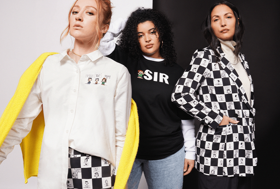 Three people stand together modeling pieces from the PEANUTS X WILDFANG collection. Background is black and white.