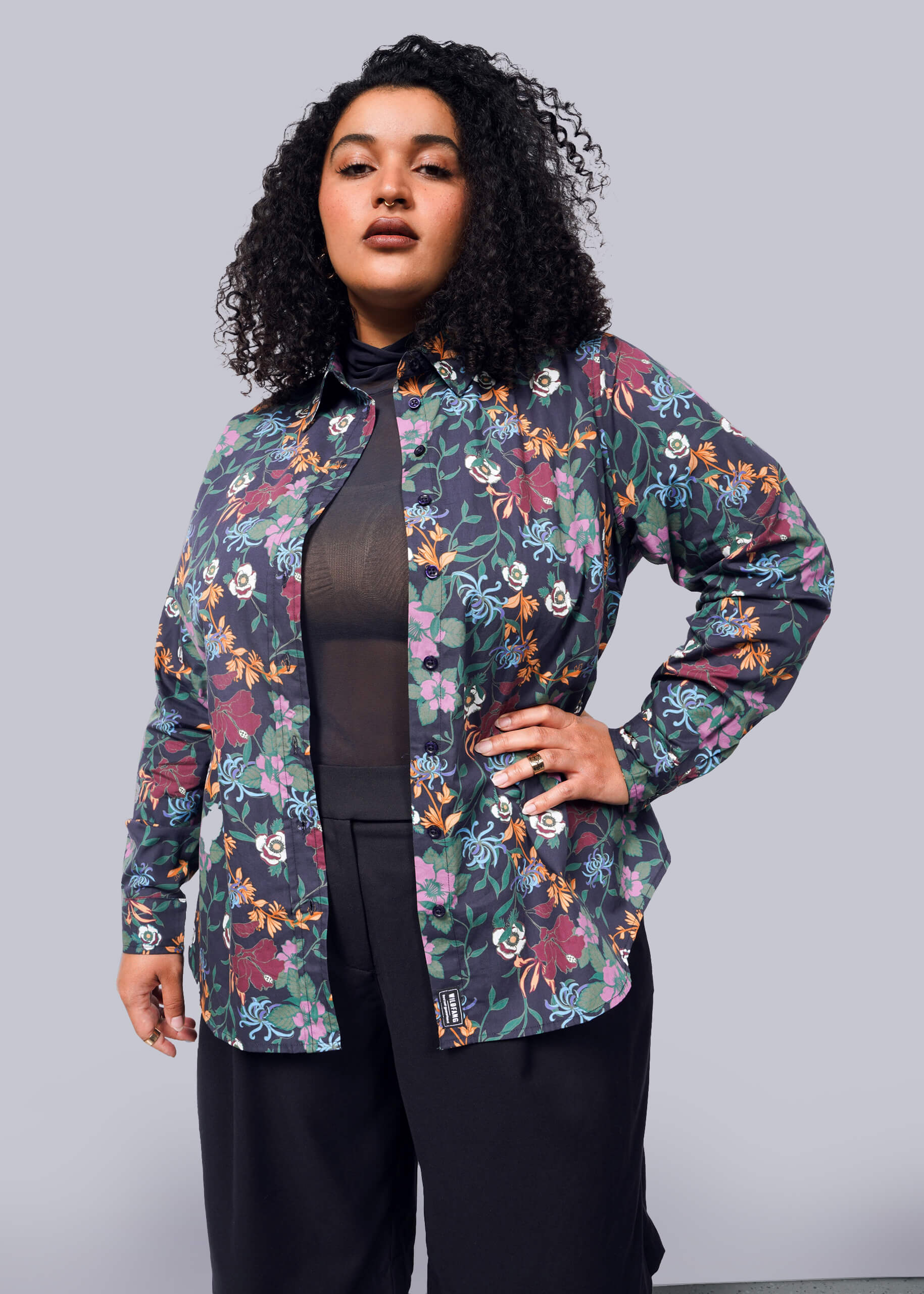 1X=Woman wearing a colorful floral shirt against a gray background