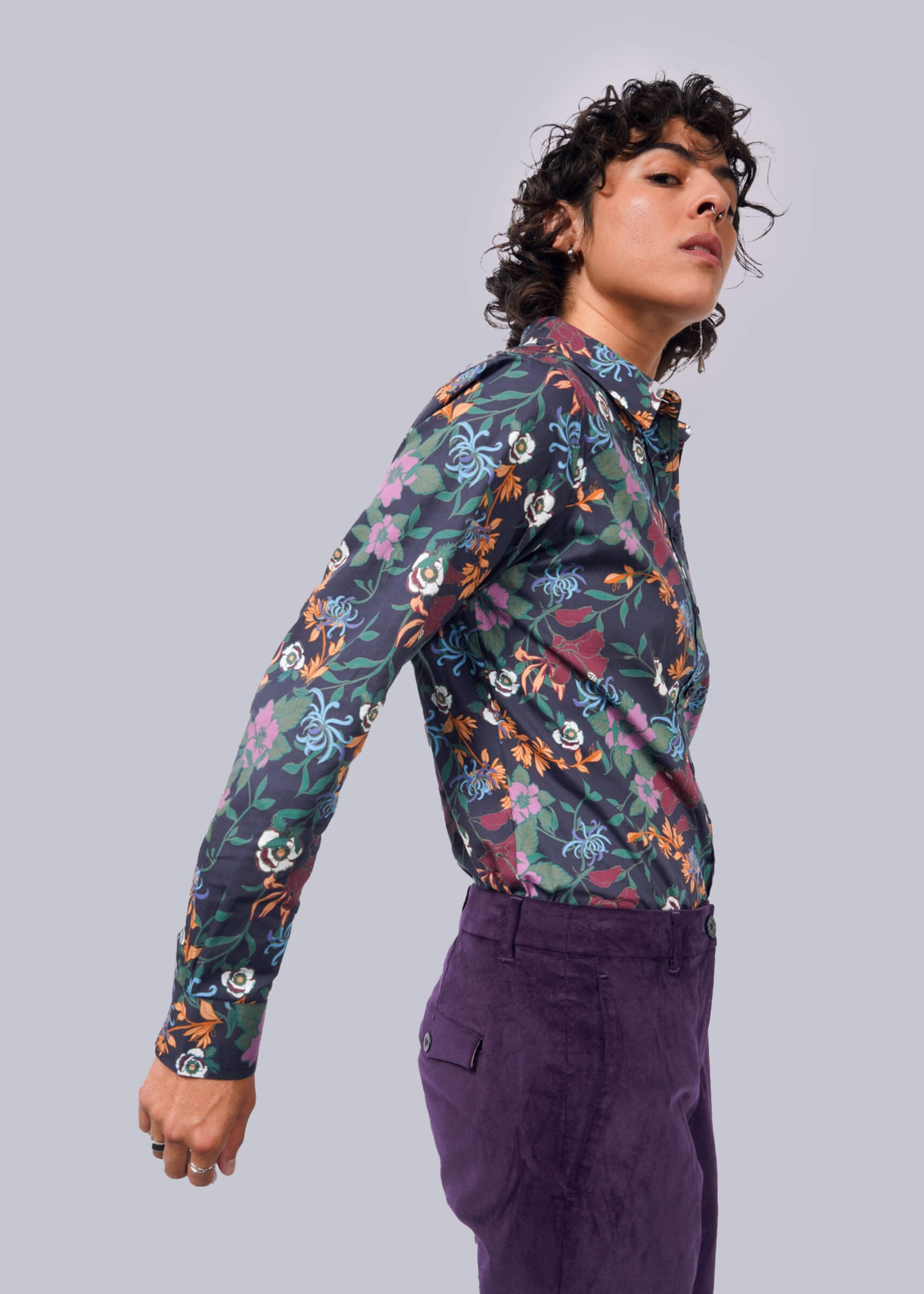 S=Person wearing a colorful floral shirt and purple pants on a gray background