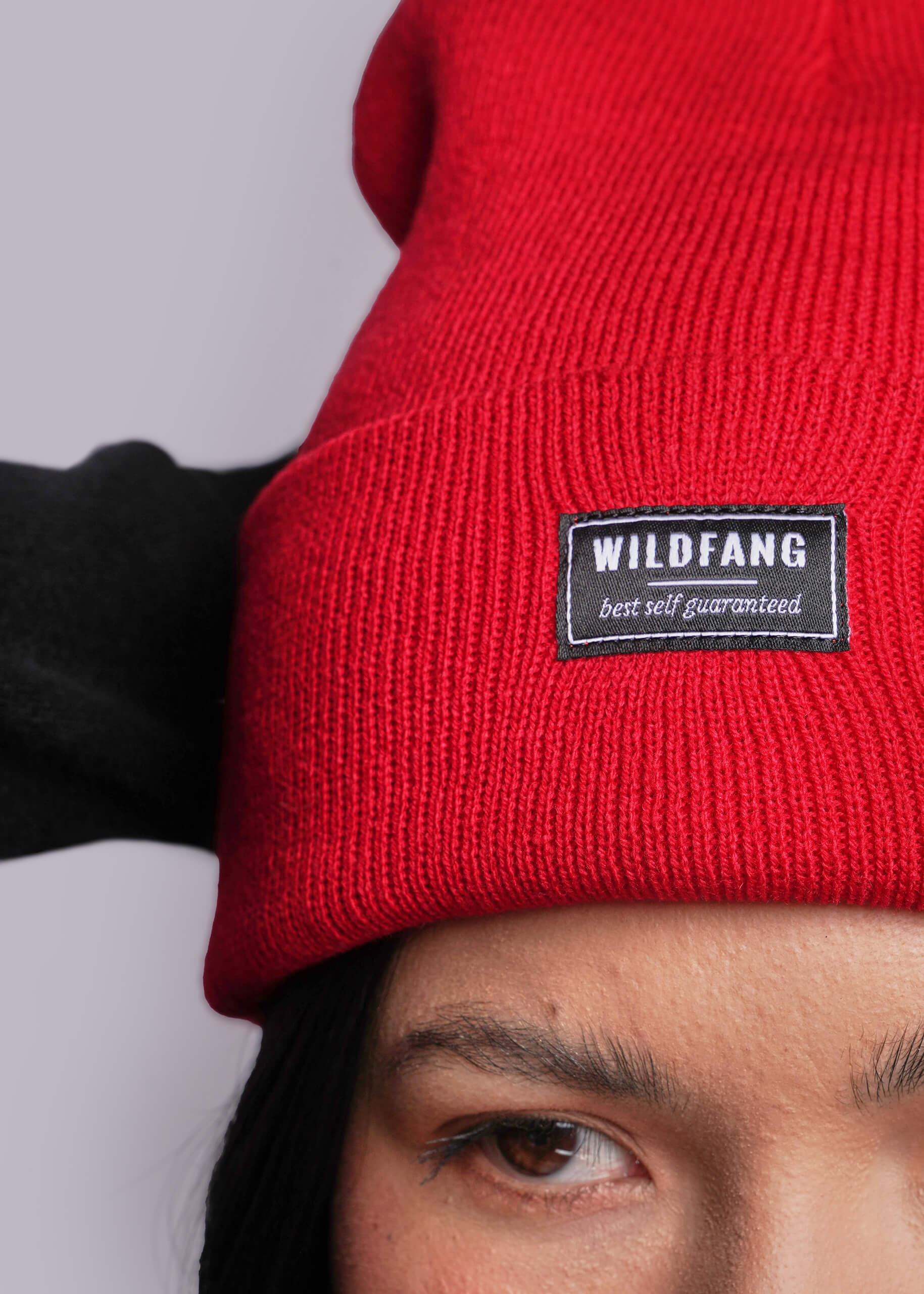 Red beanie with a 'WILDFANG' label worn by a person against a light gray background