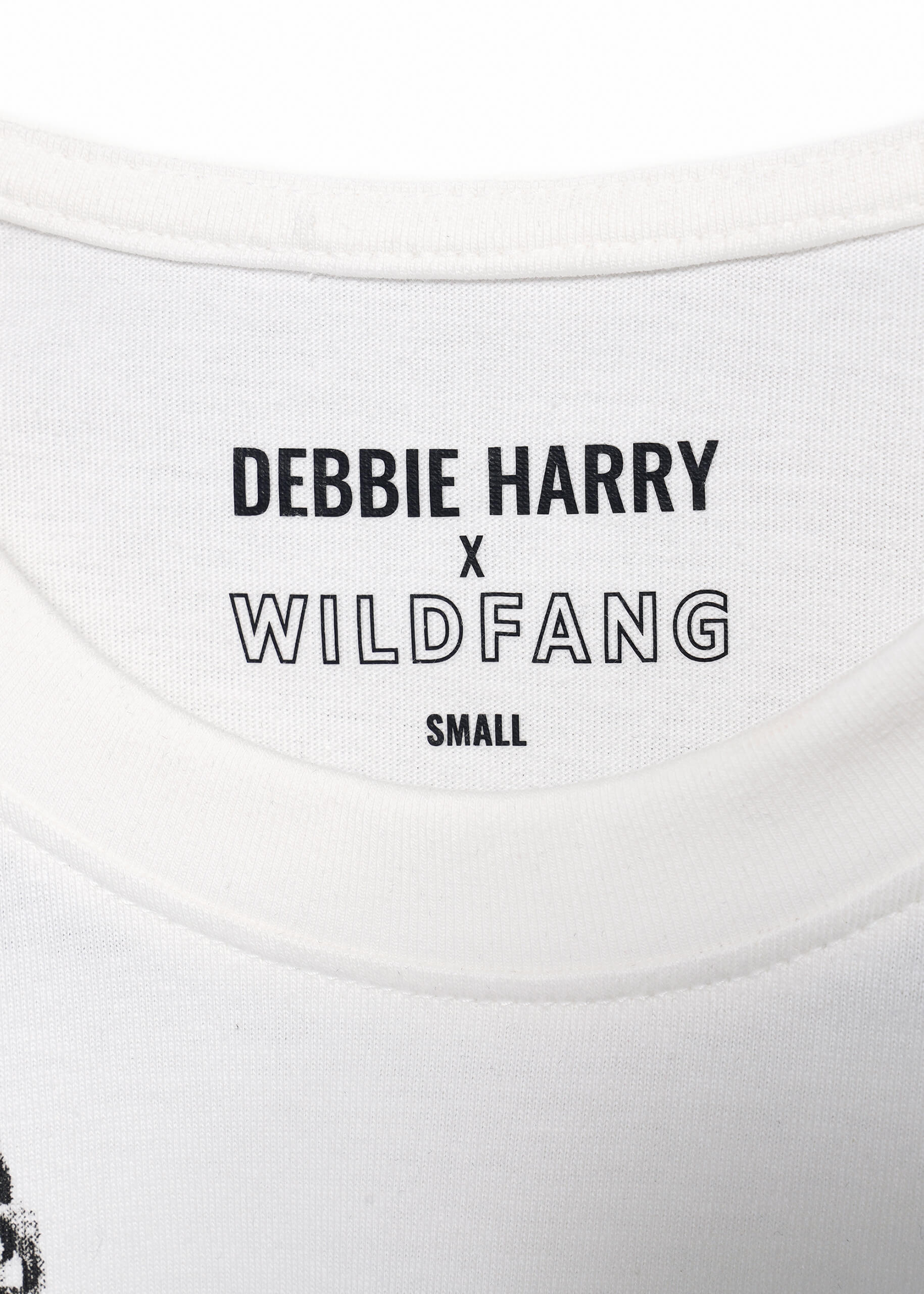S=Close-up of the neckline label on a white Debbie Harry X Wildfang Graphic Tee, featuring SMALL beneath, showcasing the punk aesthetic of the collection.