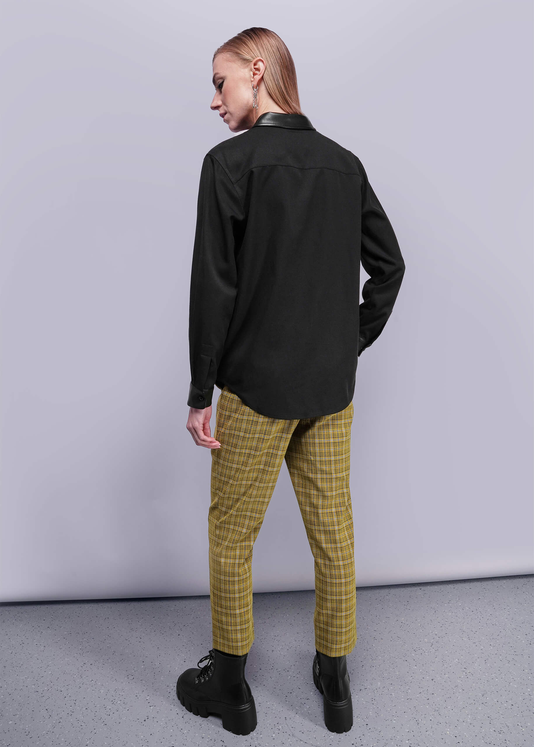 S=Person wearing a black shirt and yellow plaid pants against a gray background