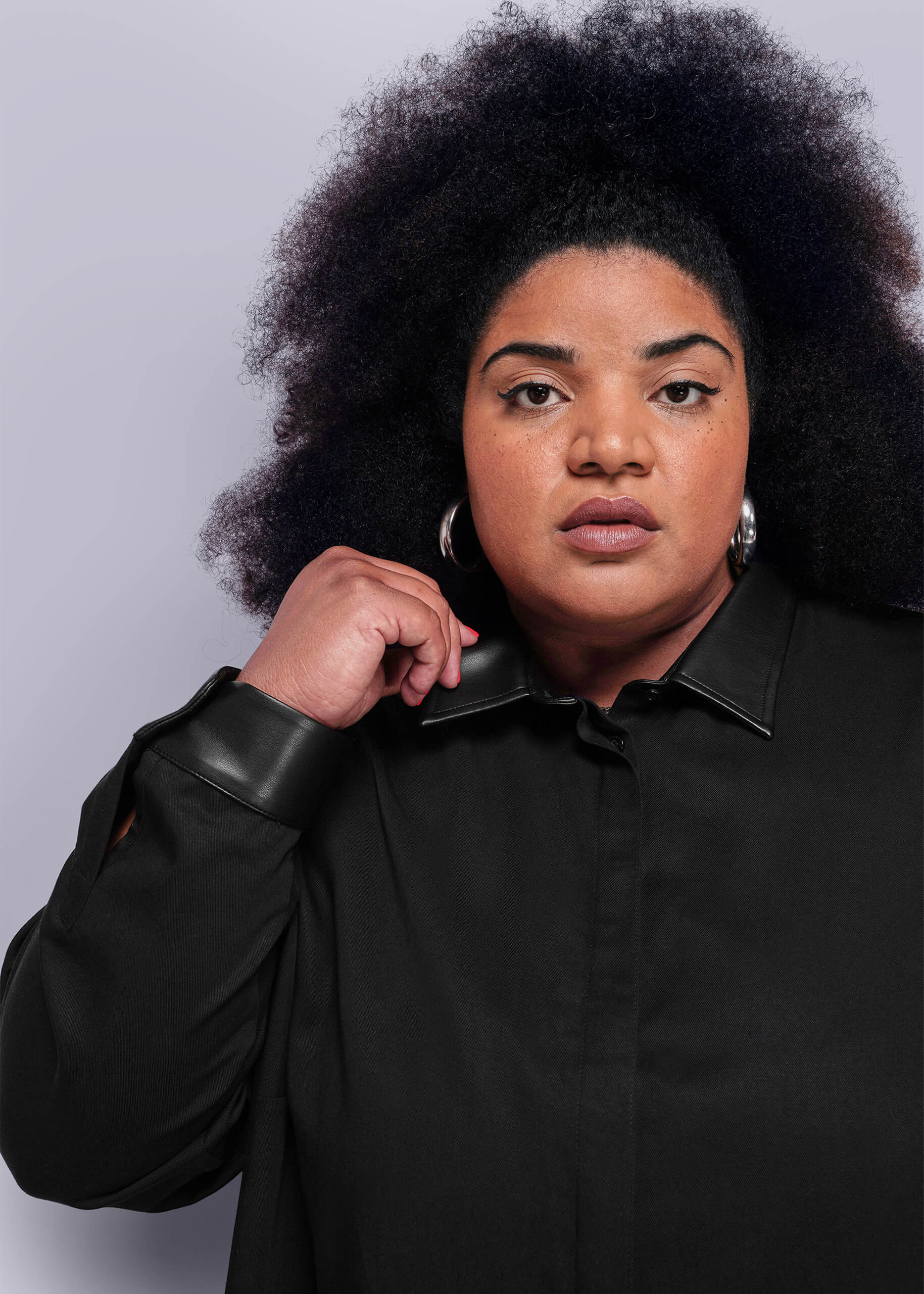 1x=Person wearing a black shirt with vegan leather collar and cuffs on a plain background