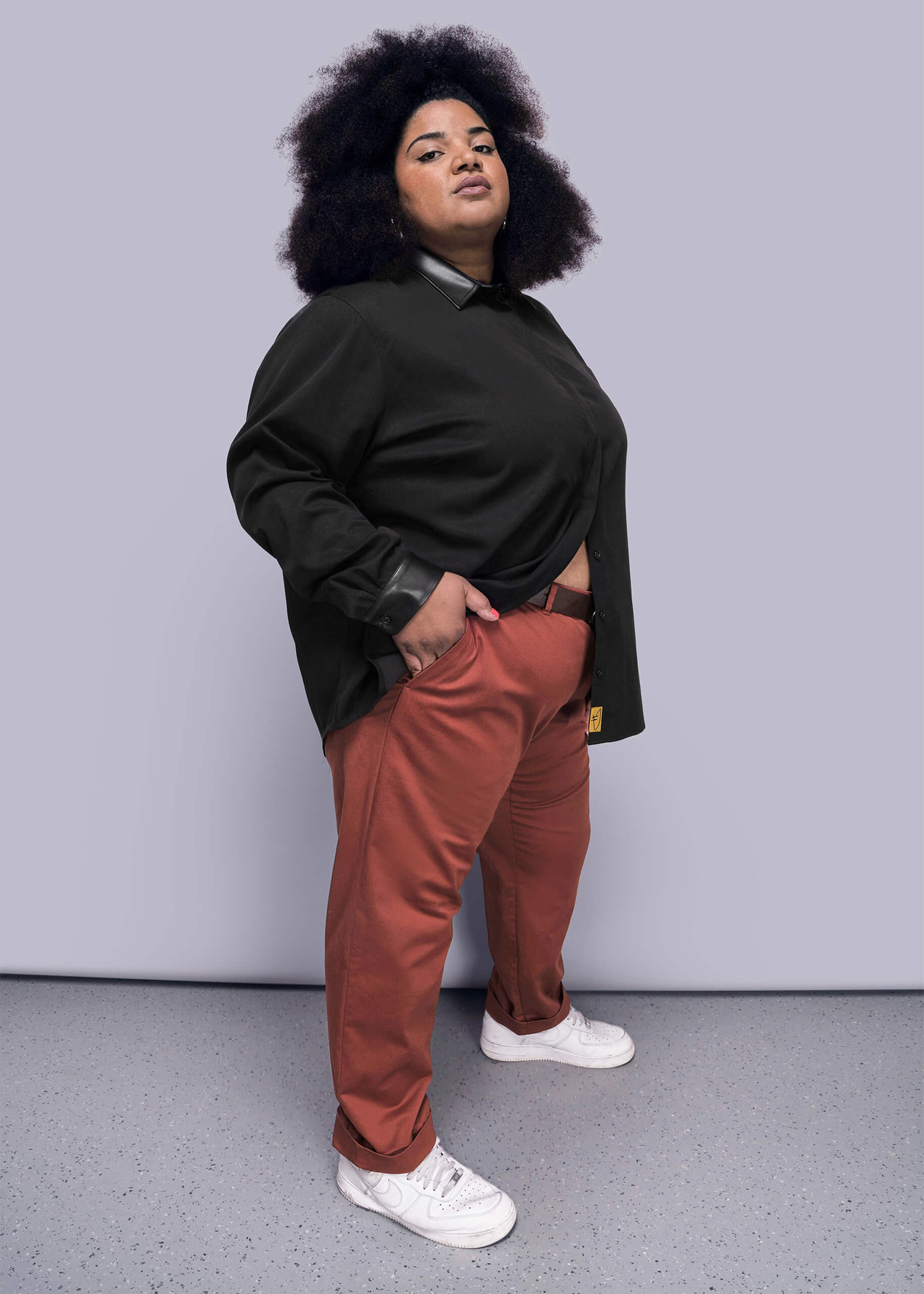 1X=Person wearing a black shirt and red pants against a gray background