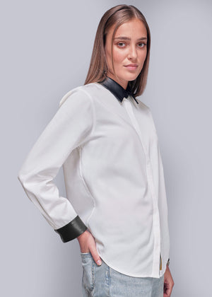 S=Side view of person wearing a white blouse with black vegan leather accents on a plain background