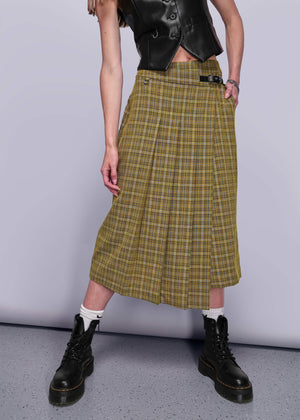 S=From chest down person wearing a yellow plaid skirt with black boots on a plain background