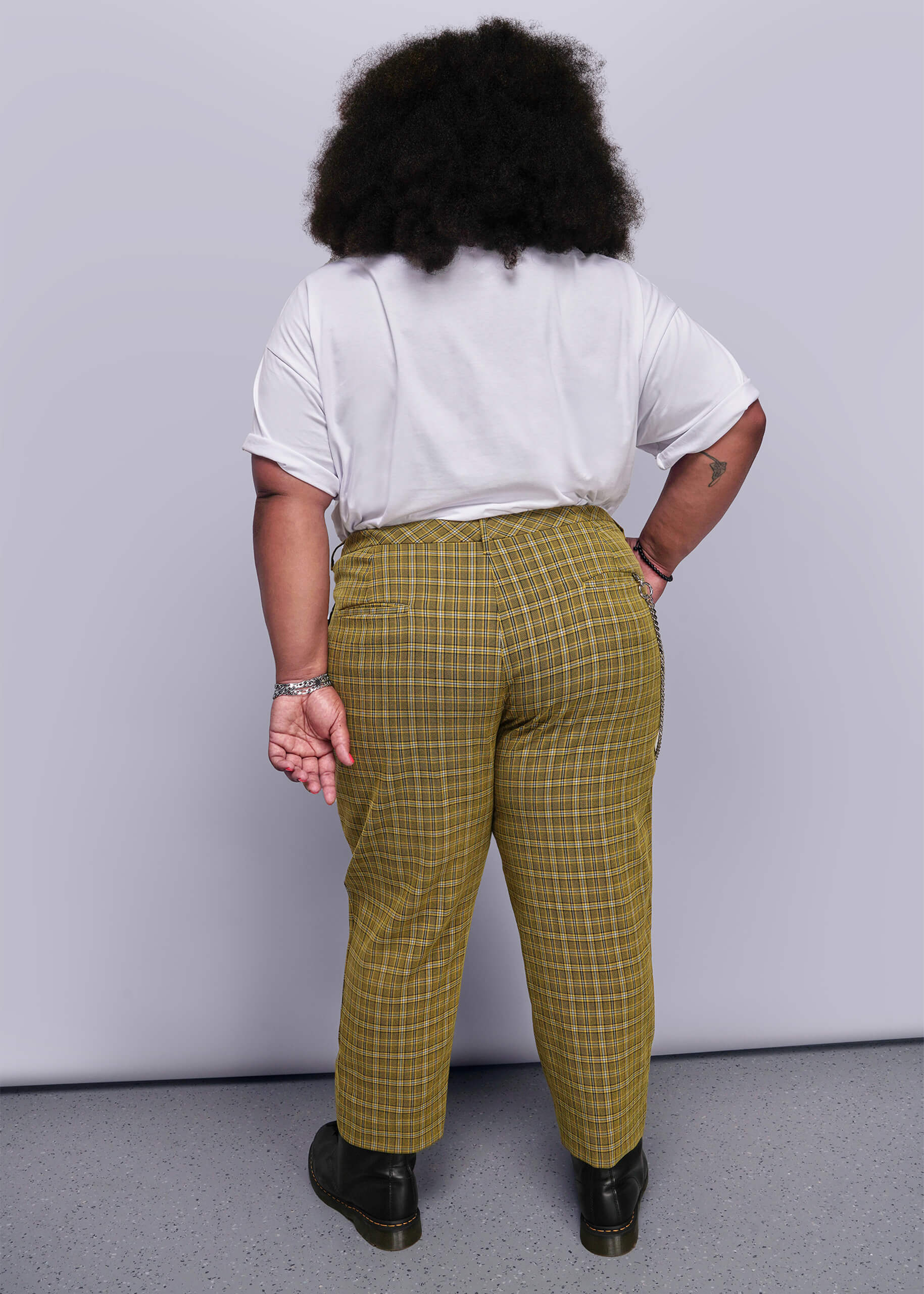 1X=Back view of person wearing a white shirt and yellow plaid pants against a plain background