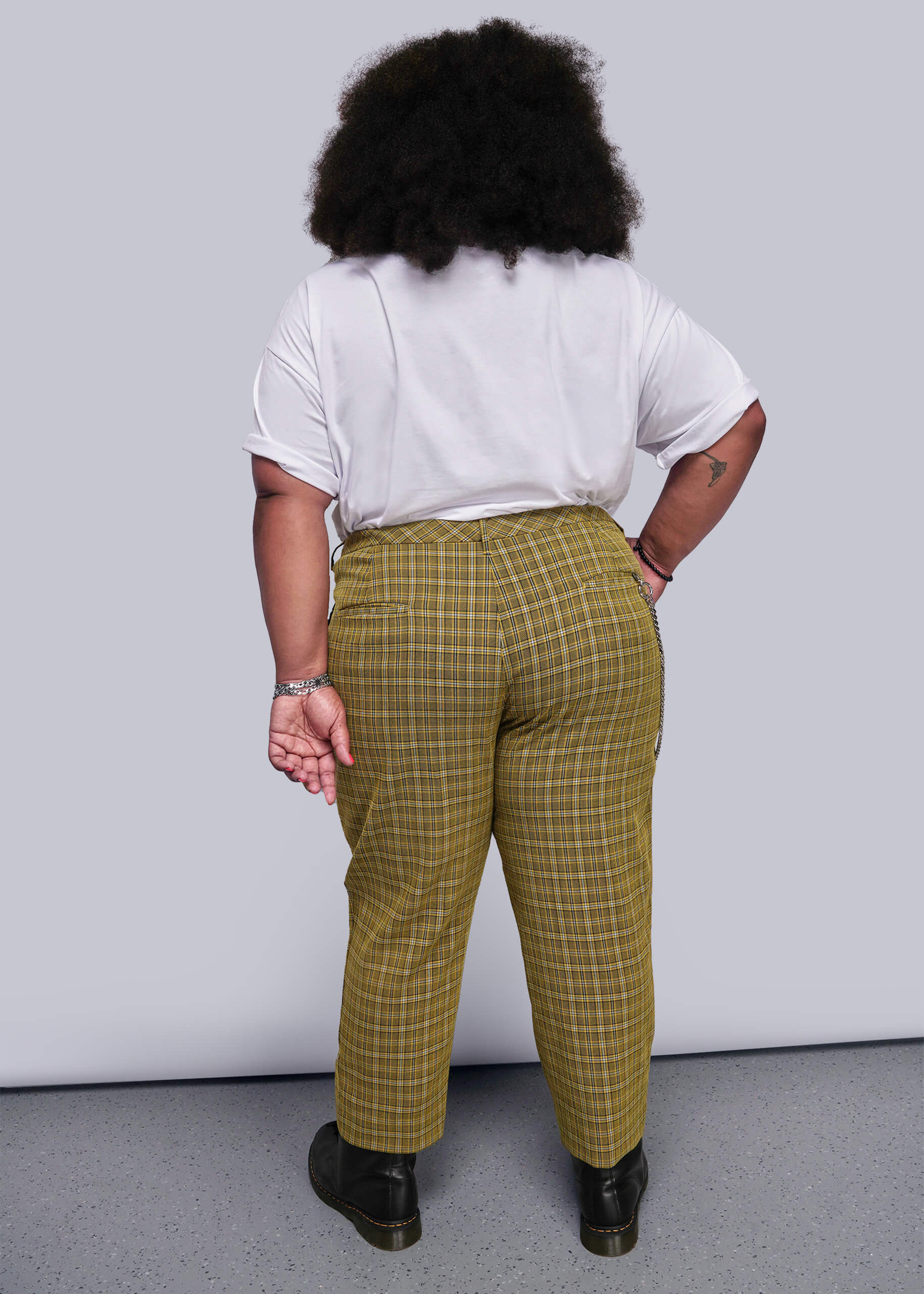1X=Back view of person wearing a white shirt and yellow plaid pants against a plain background