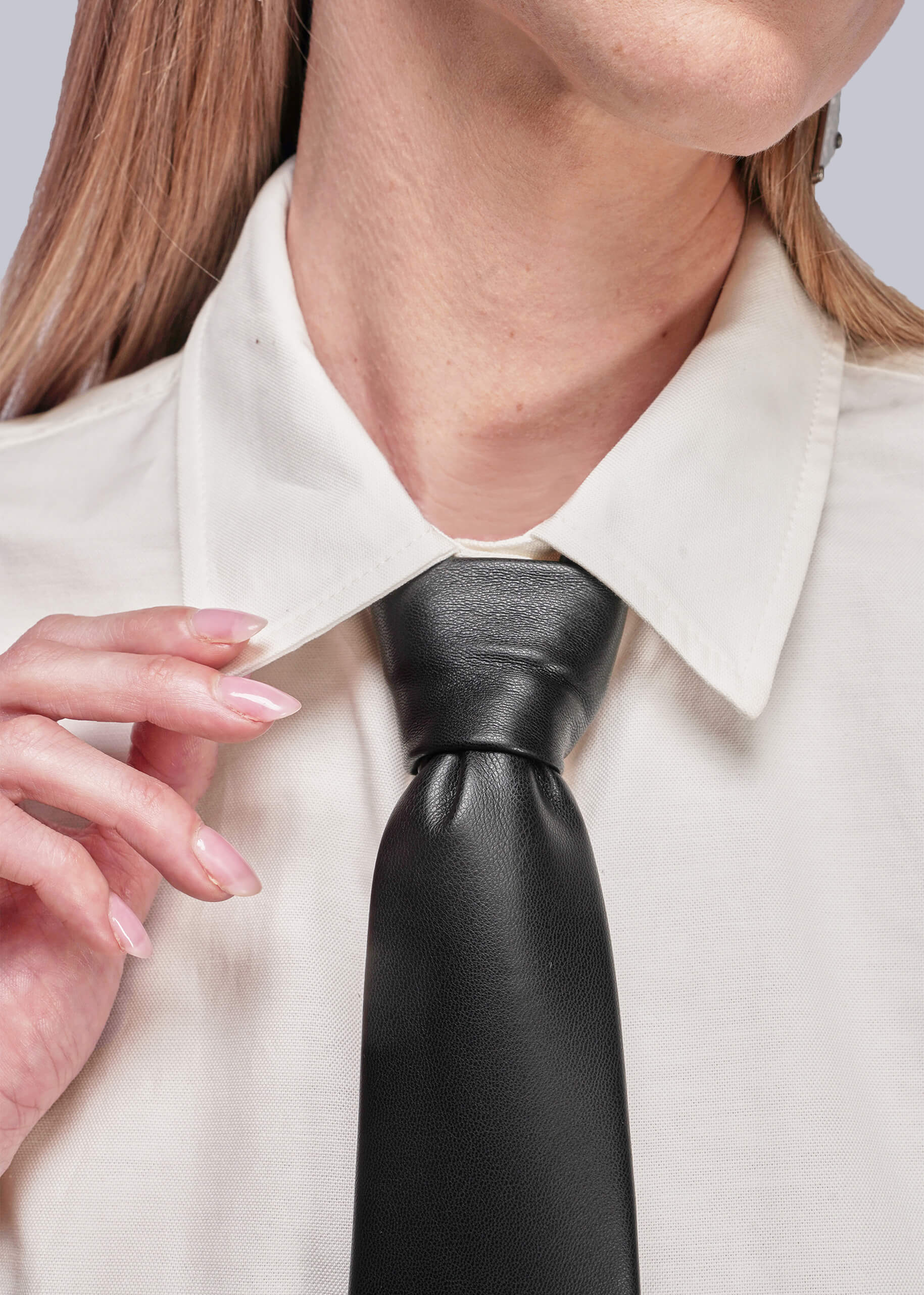 Person wearing a white shirt and black leather tie with a neutral background