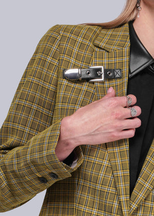 S=Person wearing a yellow plaid blazer with a black leather buckle detail on a plain background
