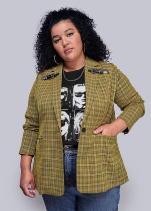 1X=Woman wearing a yellow plaid blazer over a black graphic t-shirt on a plain background