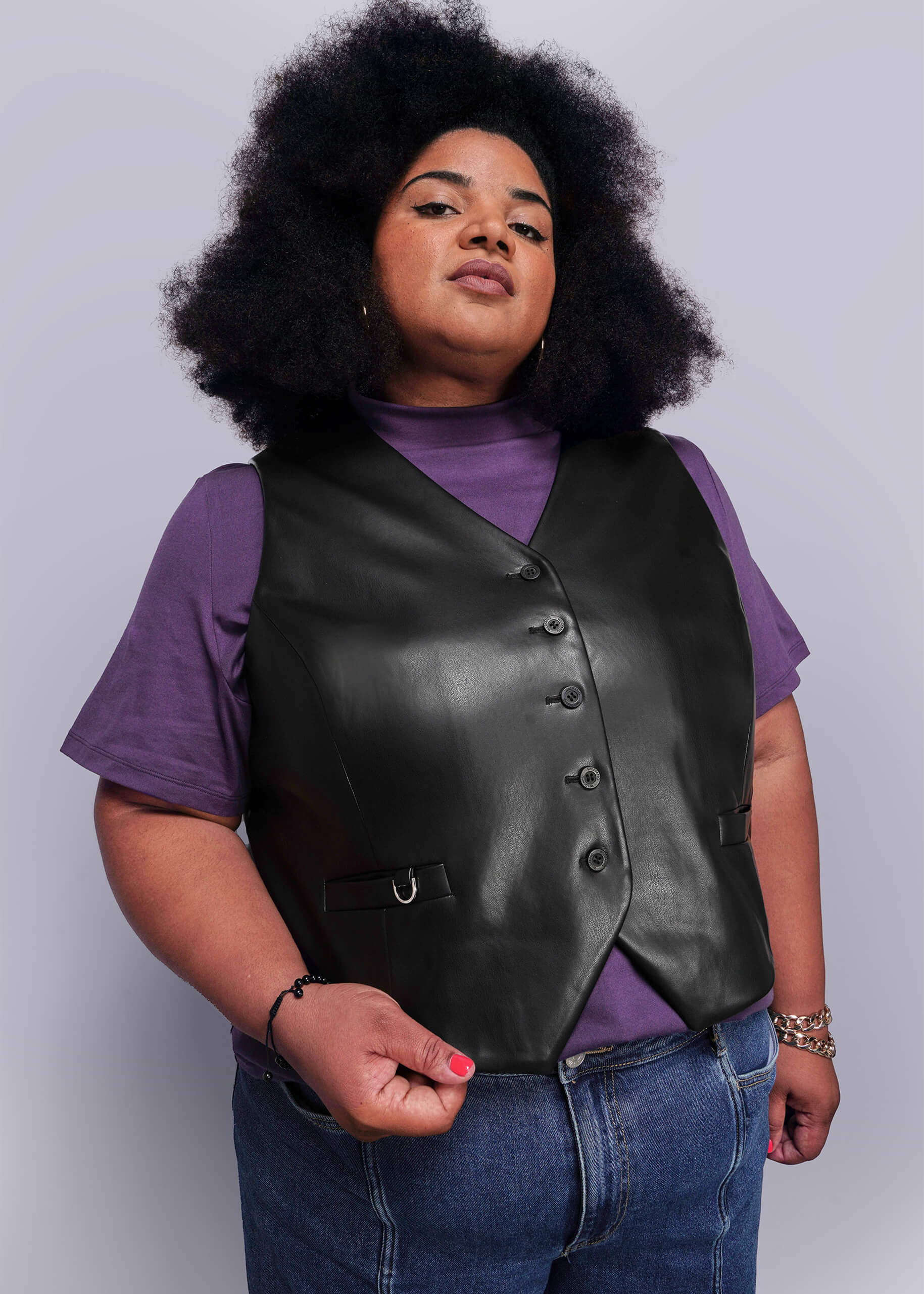 1X=Person wearing a black vegan leather vest over a purple shirt with a plain background