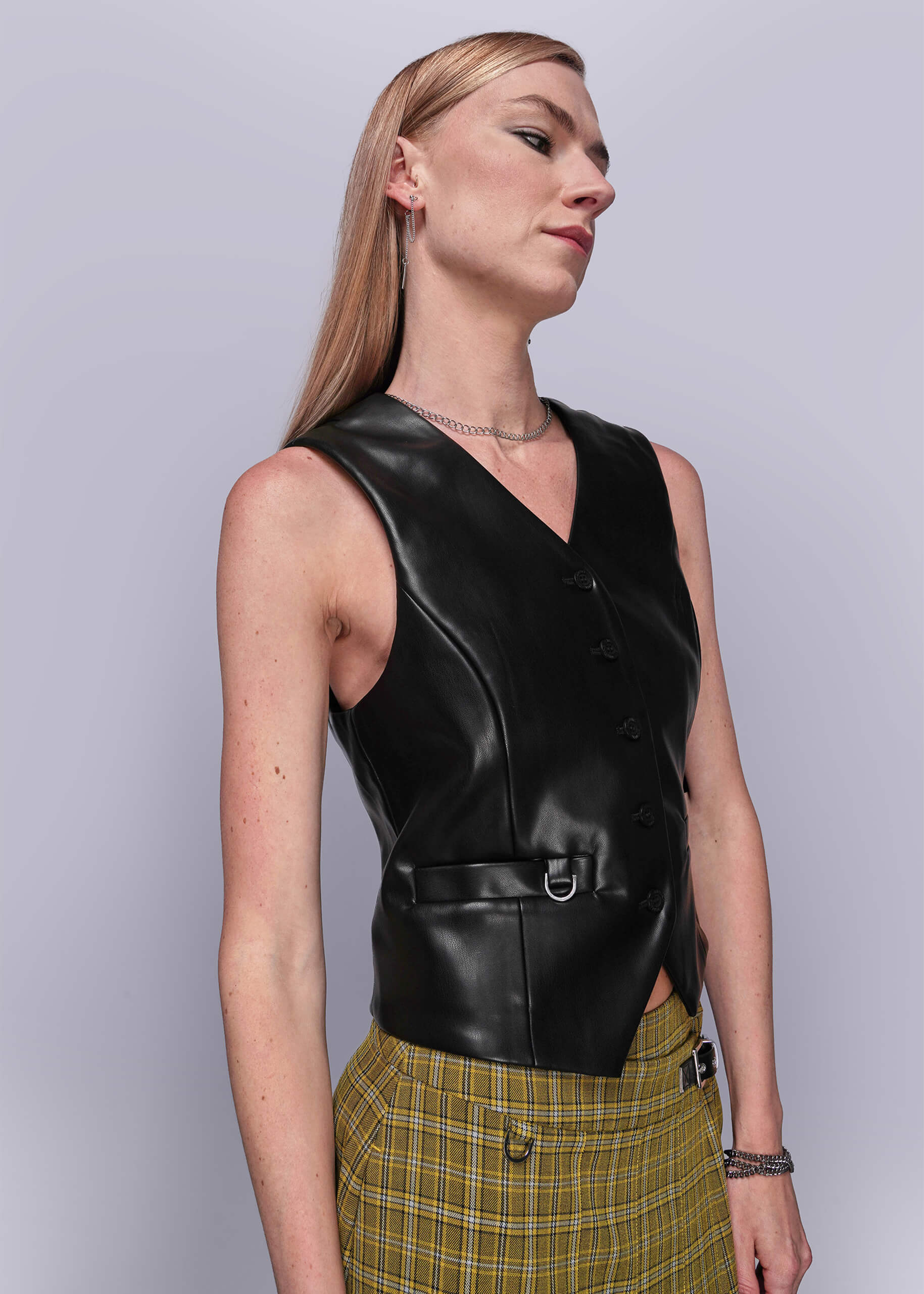 S=Person wearing a black vegan leather vest against a light gray background