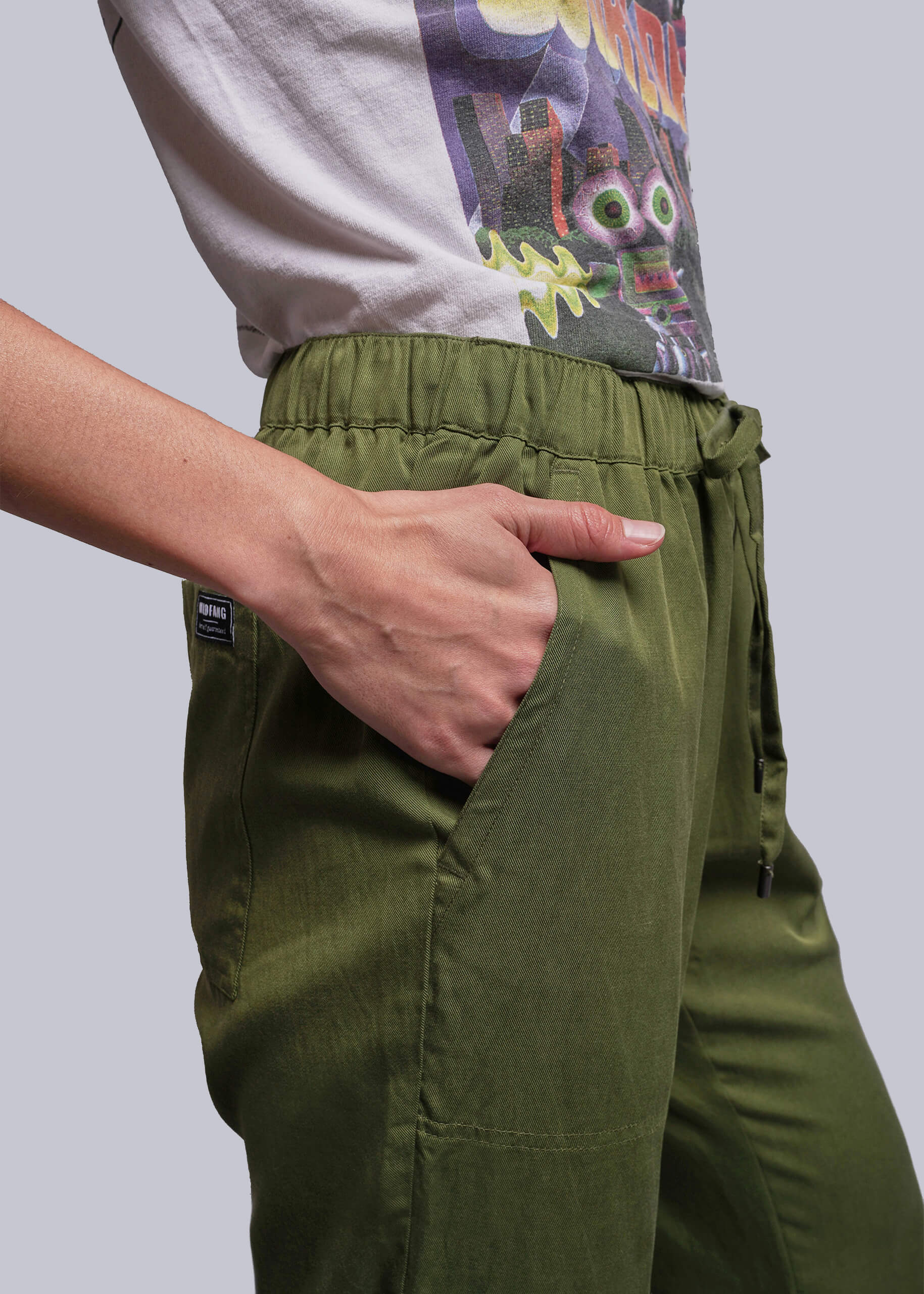 S=Person wearing green pants with a colorful graphic shirt on a plain background