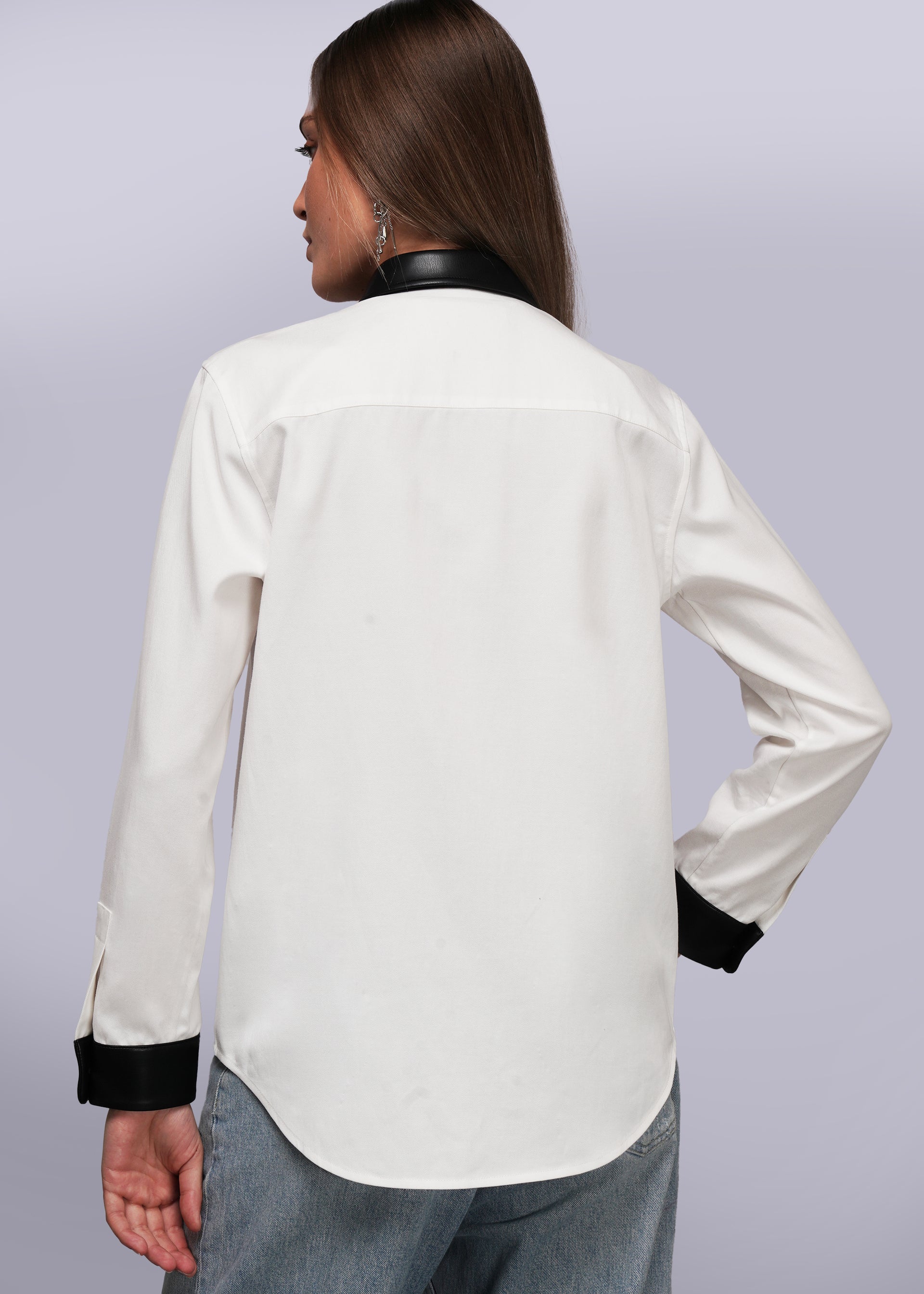 S=Back view of person wearing a white blouse with black cuffs and collar on a light gray background