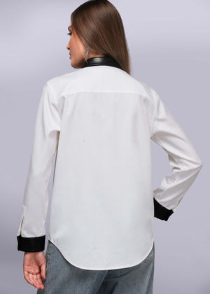 S=Back view of person wearing a white blouse with black cuffs and collar on a light gray background