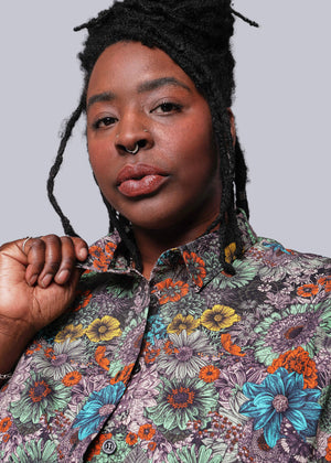 1X=Person wearing a colorful floral patterned shirt against a plain background
