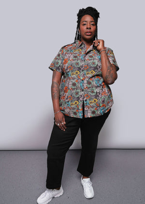 1X=Person wearing a floral shirt and black pants against a plain background