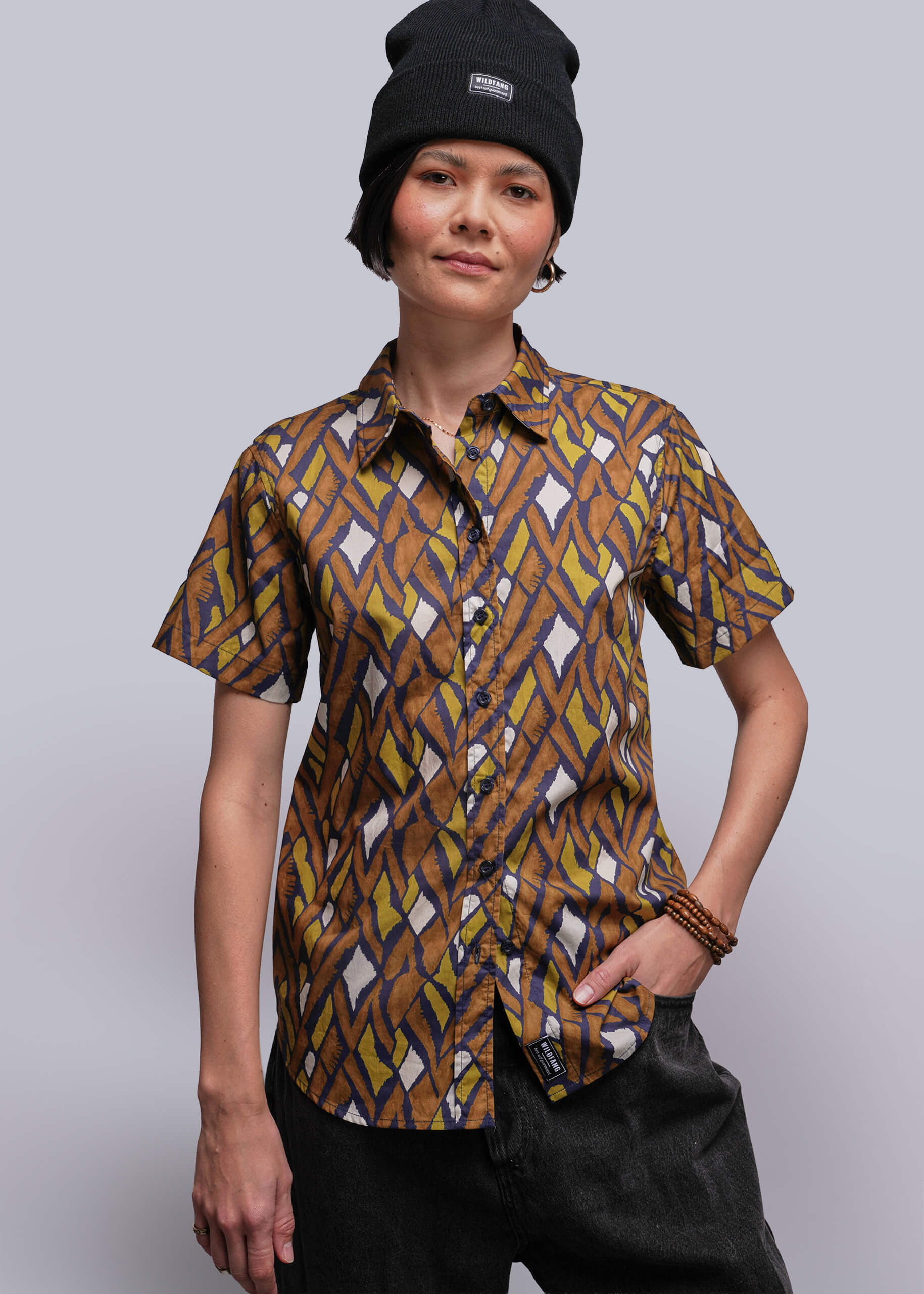 Person wearing a patterned shirt and black beanie against a plain background