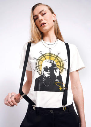 S= A person with long hair wearing the Debbie Harry X Wildfang Graphic Tee, featuring a graphic of someone in sunglasses, showcases punk fashion with layered necklaces and black straps against a plain background.