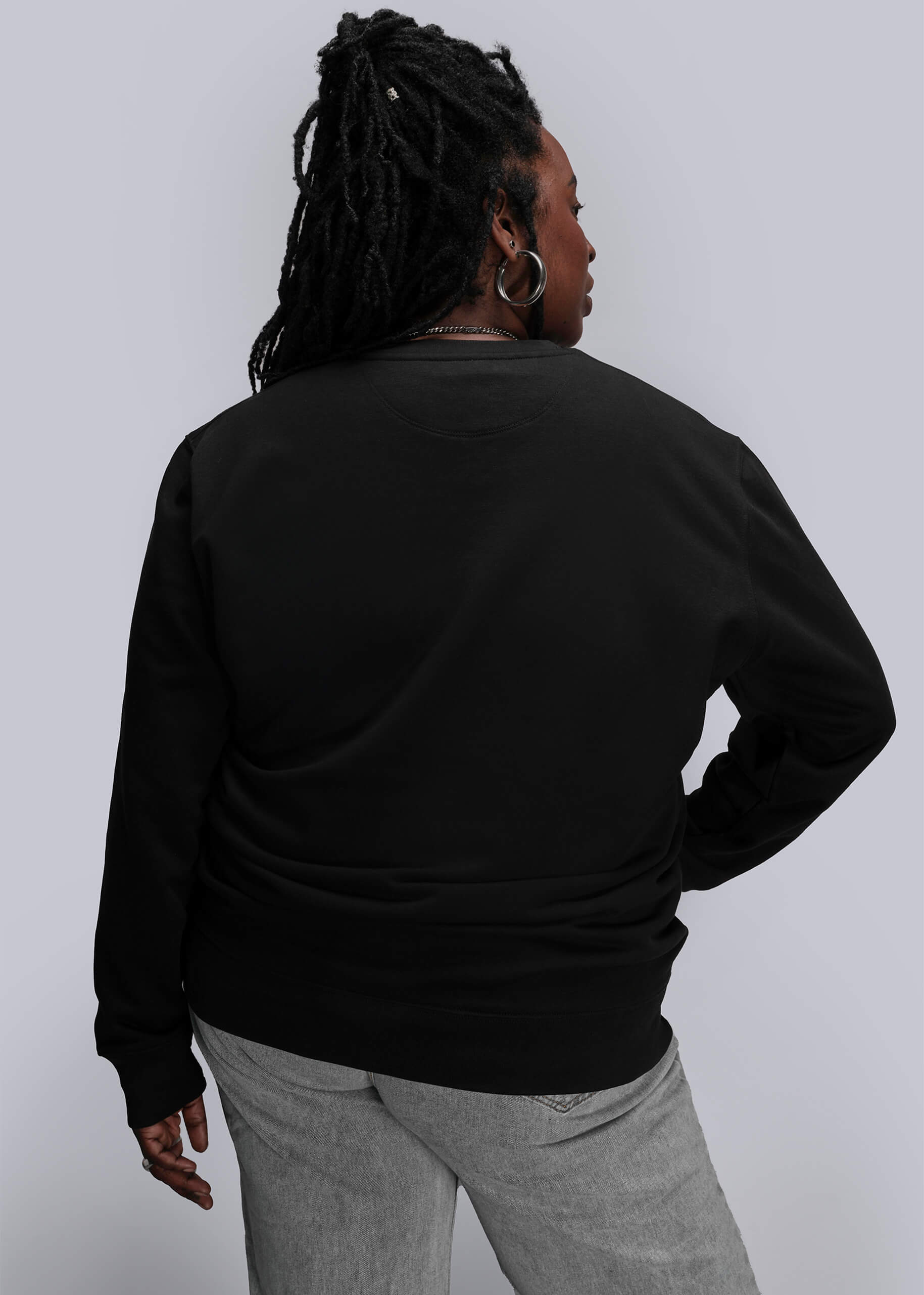 1X=Person wearing a black sweatshirt and gray pants against a white background