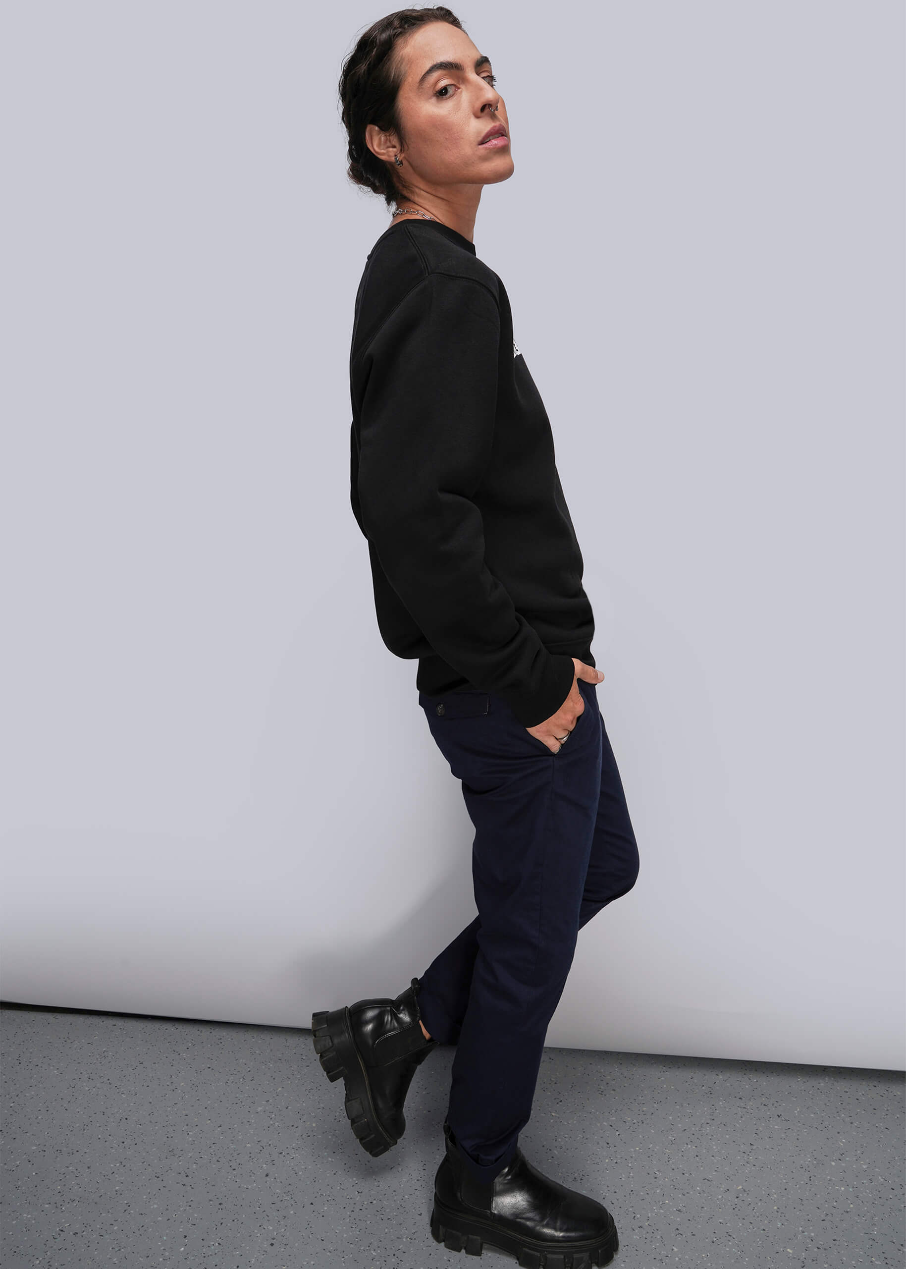 S=Person wearing a black sweatshirt and dark pants against a plain background