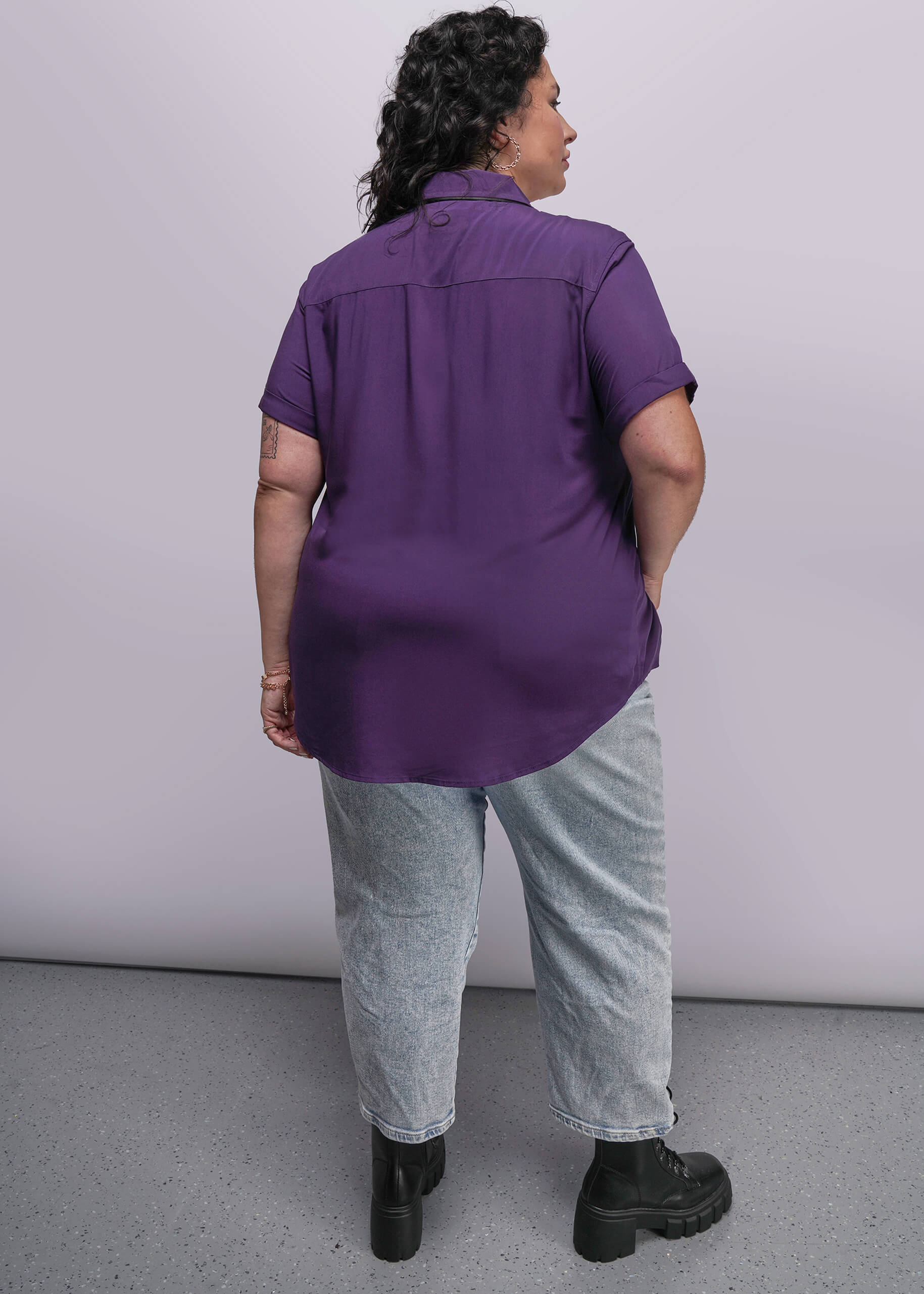 1X=Person wearing a purple shirt and gray pants against a white background
