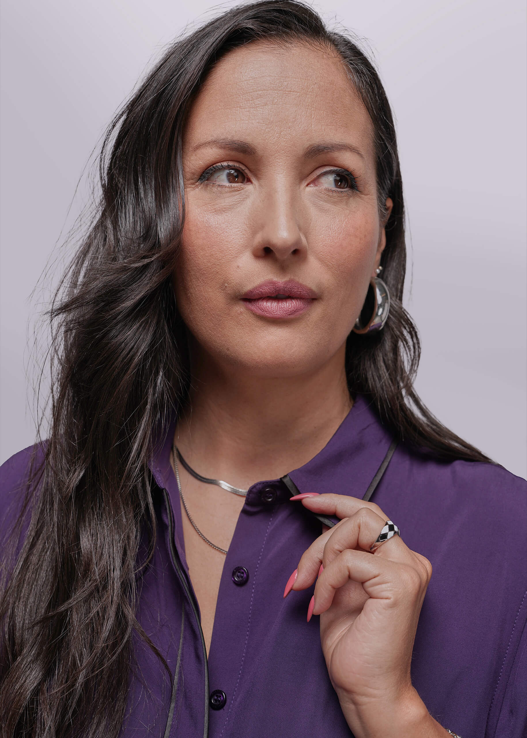 S=Woman wearing a purple shirt against a plain background