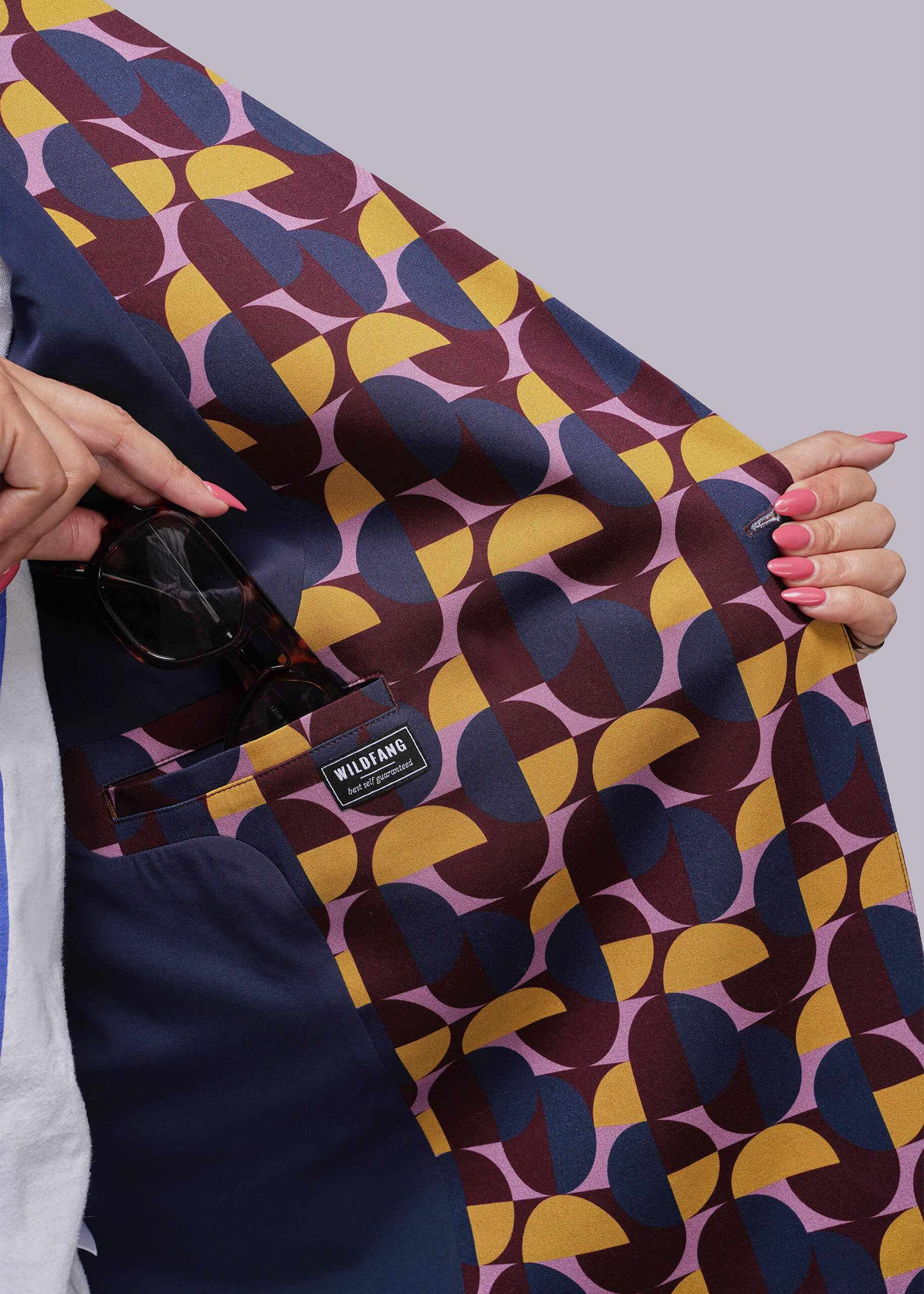 S=Colorful geometric-patterned fabric held by a person with a visible brand label.
