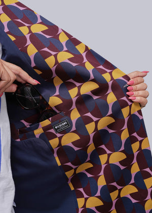 S=Colorful geometric-patterned fabric held by a person with a visible brand label.