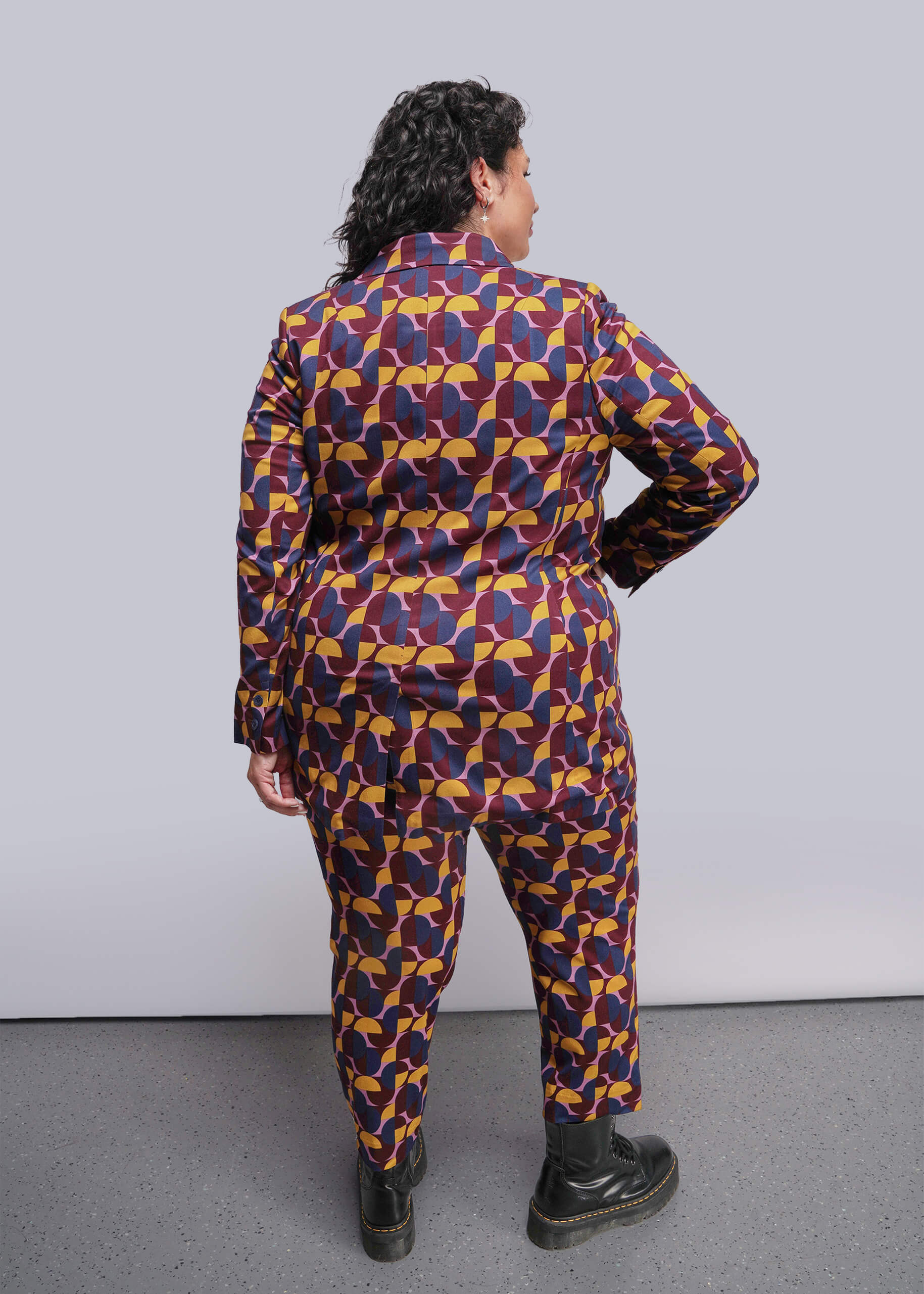 1X=Person wearing a colorful geometric patterned outfit against a plain background