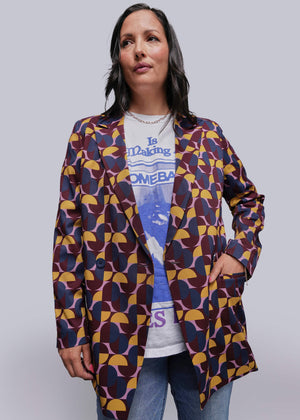 S=Woman wearing a patterned jacket over a graphic t-shirt on a plain background