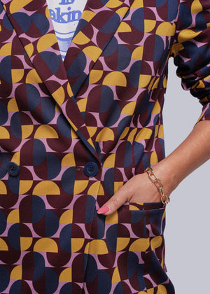 S=Patterned outfit with geometric design in purple, yellow, and blue on a plain background