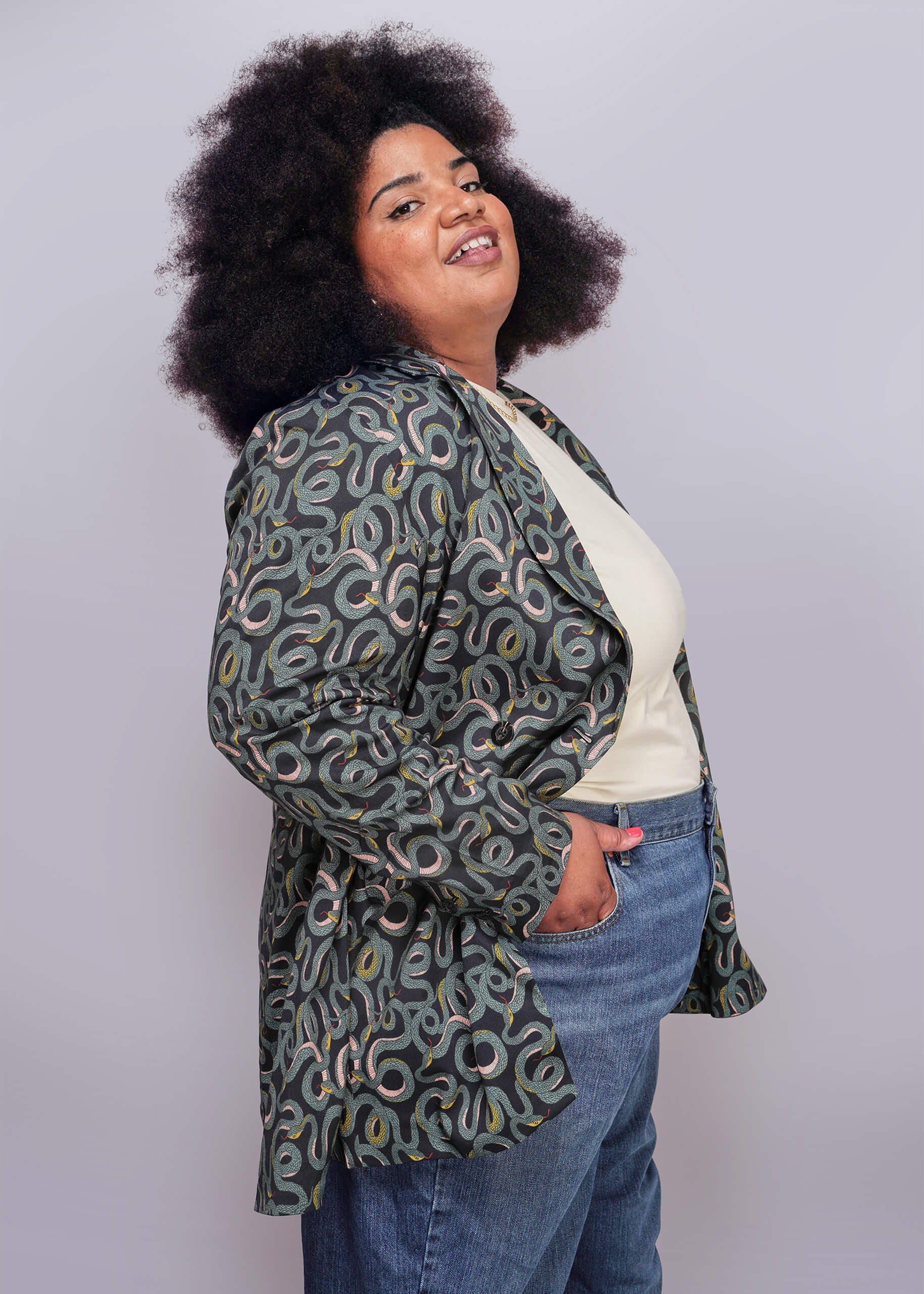 1X=Person wearing a patterned jacket and jeans on a plain background