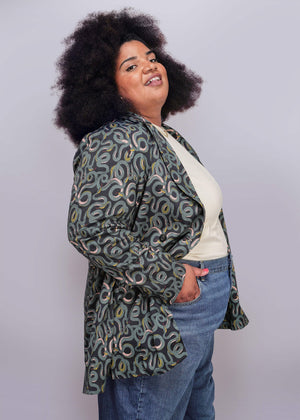 1X=Person wearing a patterned jacket and jeans on a plain background