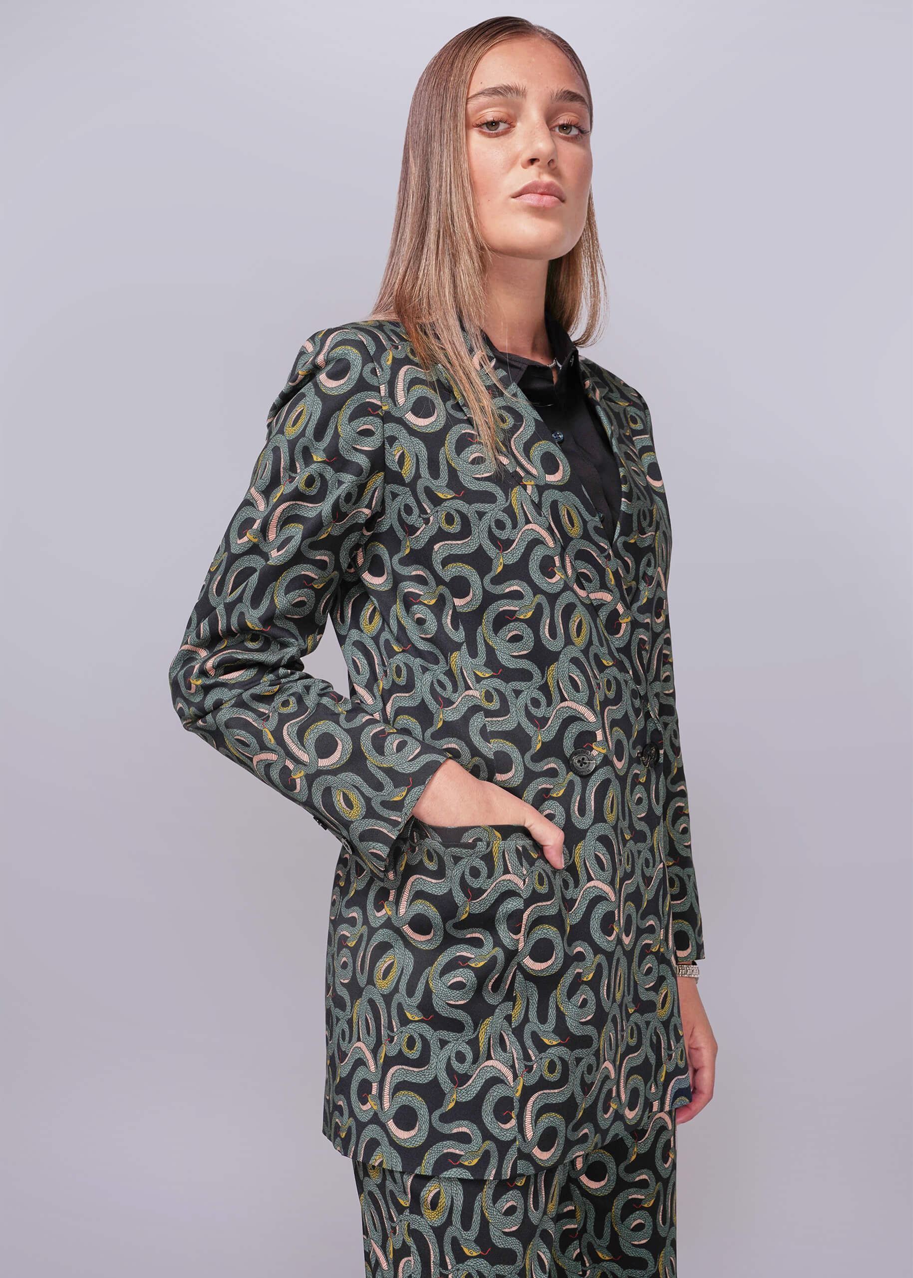 S=Woman wearing a patterned suit against a plain background
