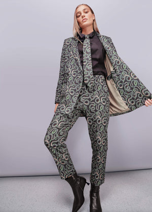 S=Woman wearing a patterned suit with a cape on a plain background