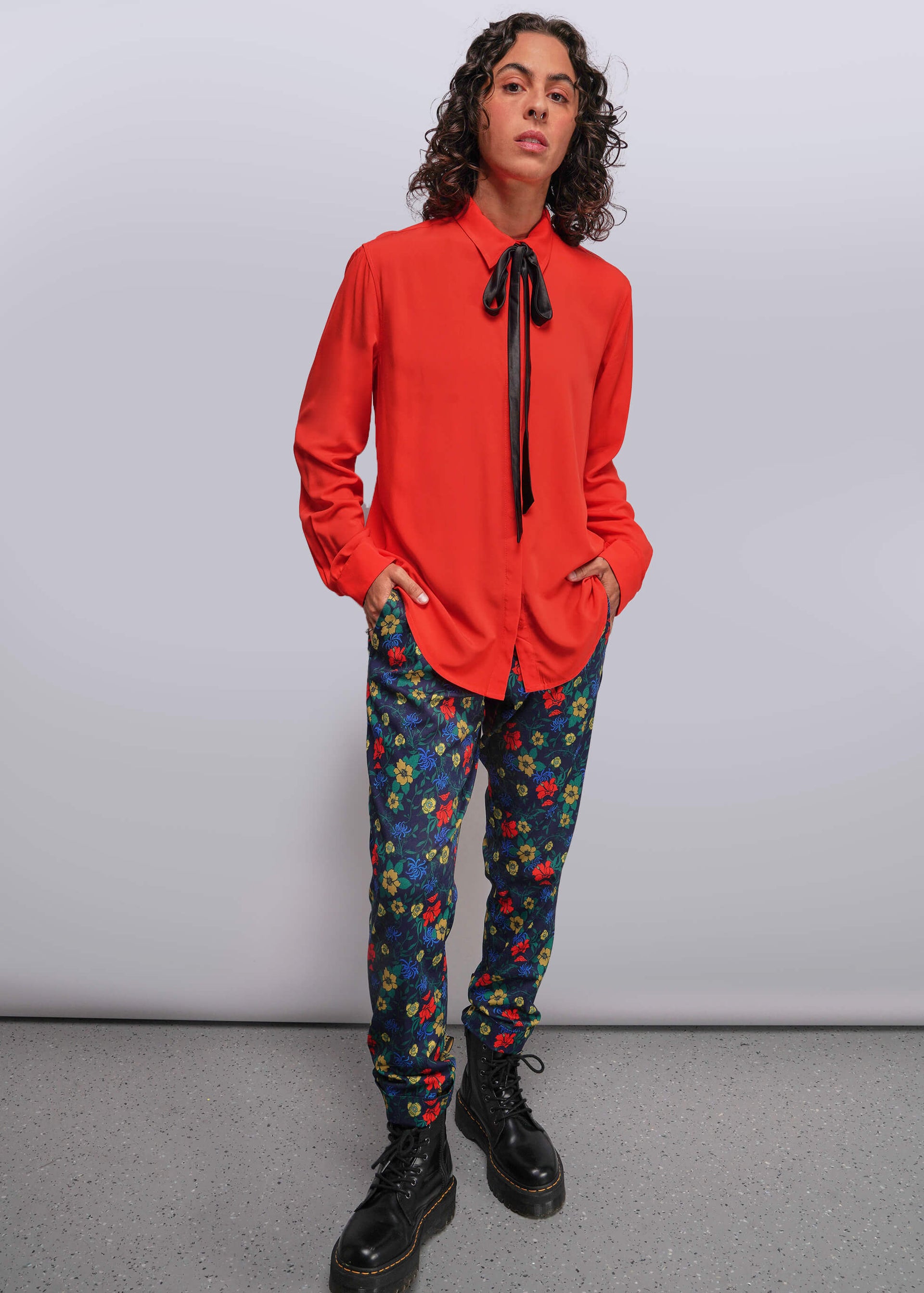 S=Person wearing a red shirt and colorful floral pants against a plain background