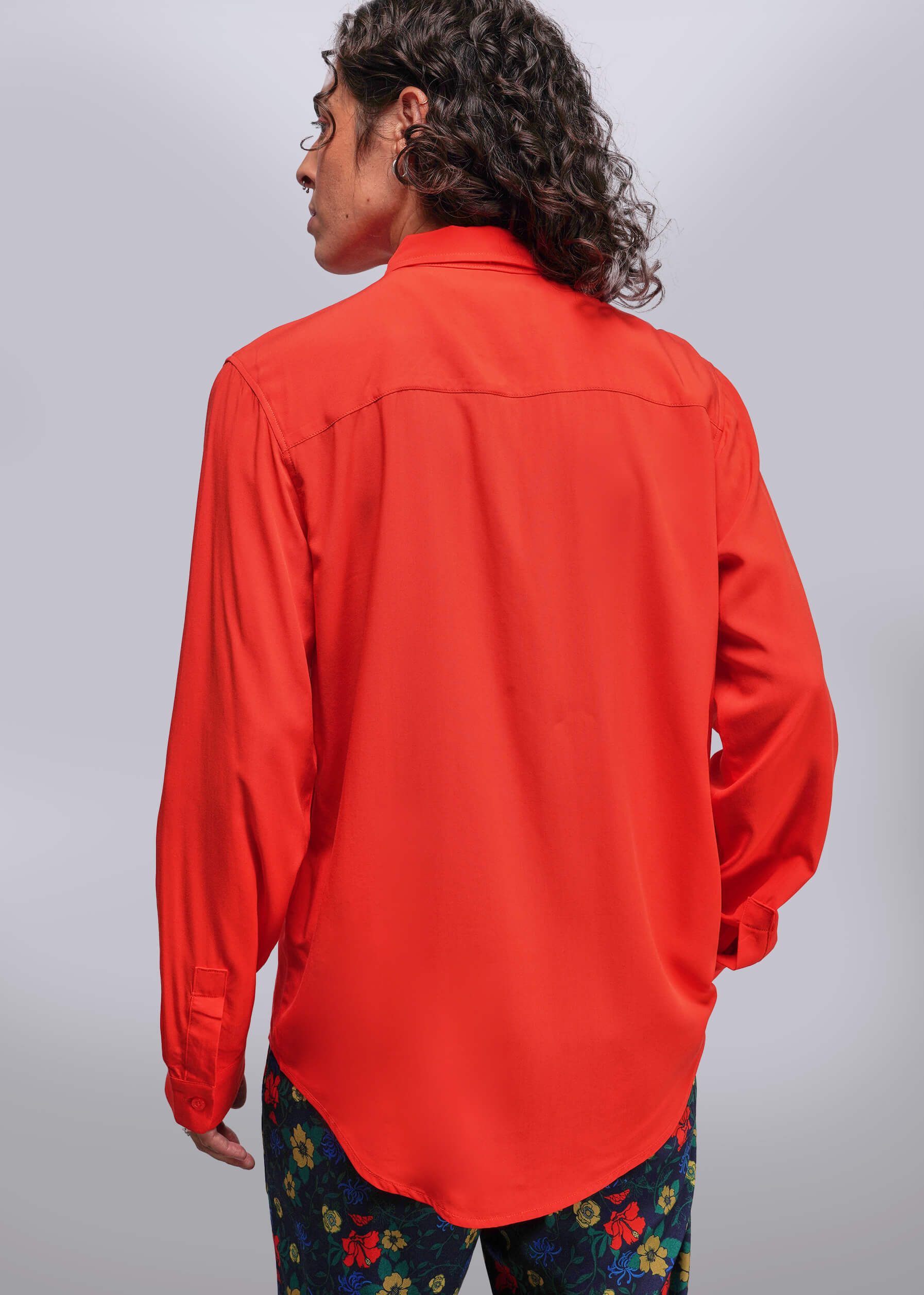 S=Person wearing a bright red shirt with colorful pants on a plain background