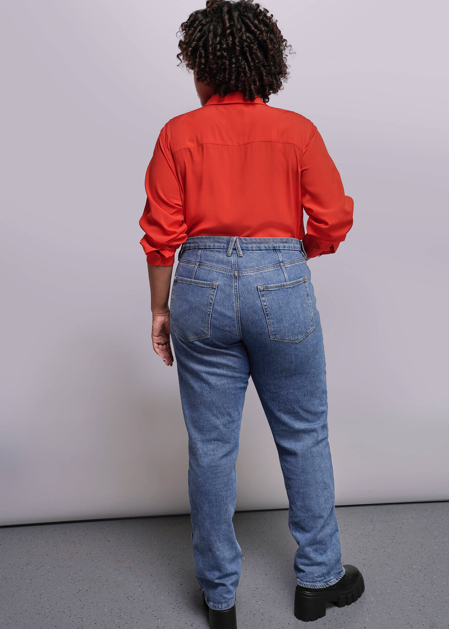 1X=Person wearing a red shirt and blue jeans from behind on a plain background