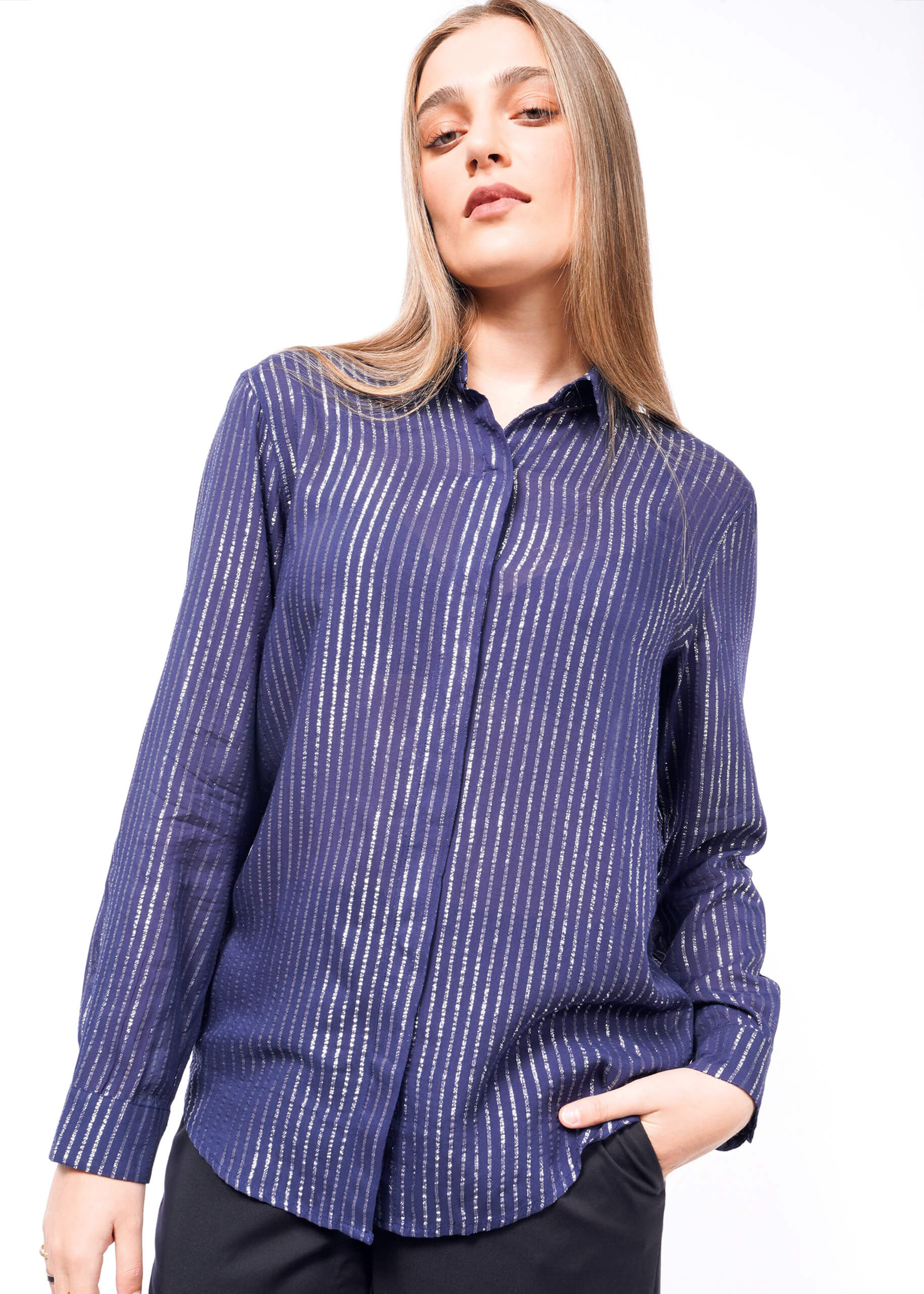 S= A person with long hair wearing The Empower Sheer Pinstripe Long Sleeve Button Up, characterized by a relaxed fit and metallic pinstripes, tilts her head and poses with one hand in a pocket against a plain white backdrop.