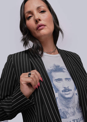 S=Woman wearing a black pinstripe blazer over a graphic t-shirt with a plain background