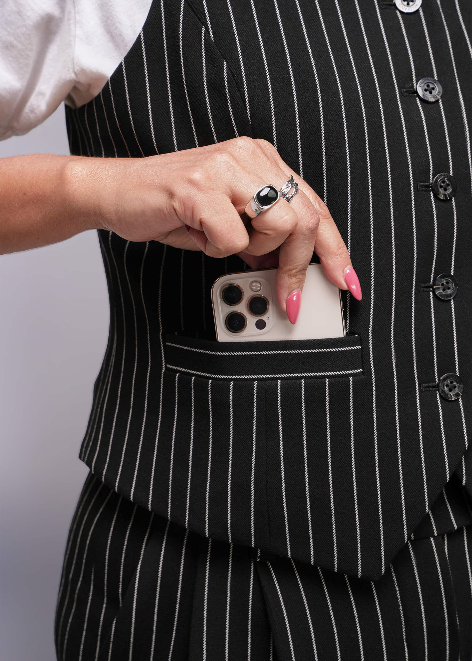 1X=Person wearing a black pinstripe suit with a phone in the pocket against a neutral background