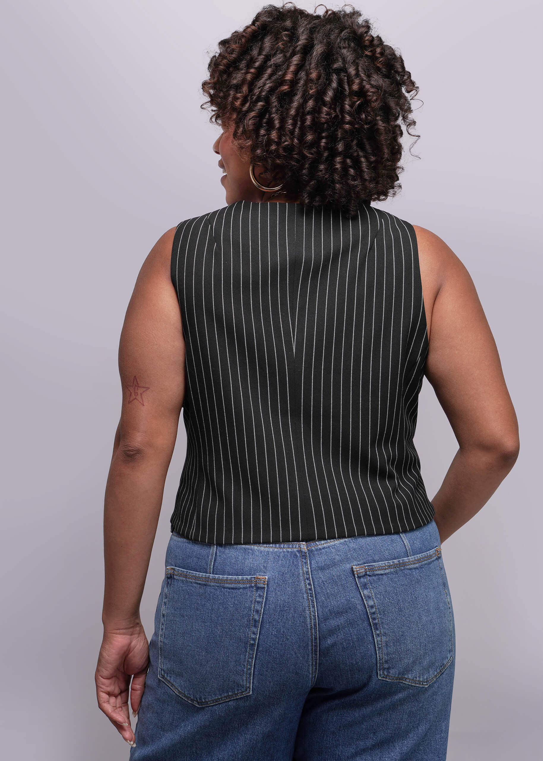 1X=Person wearing a black pinstripe sleeveless top and blue jeans against a plain background