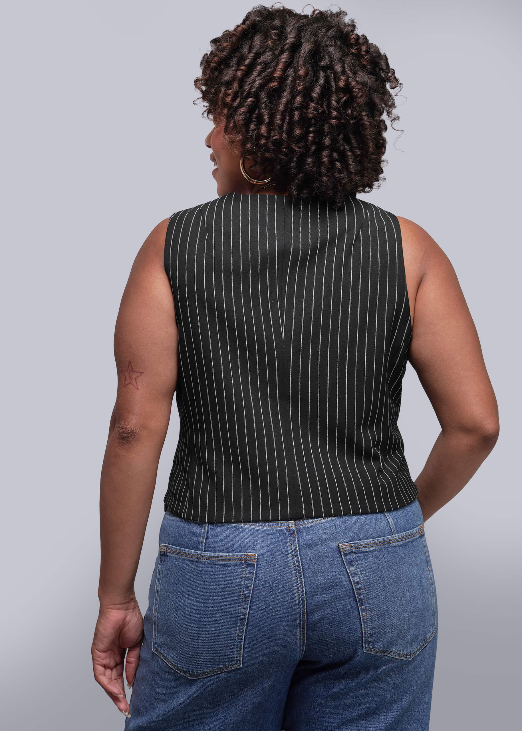 1X=Person wearing a black pinstripe sleeveless top and blue jeans against a plain background