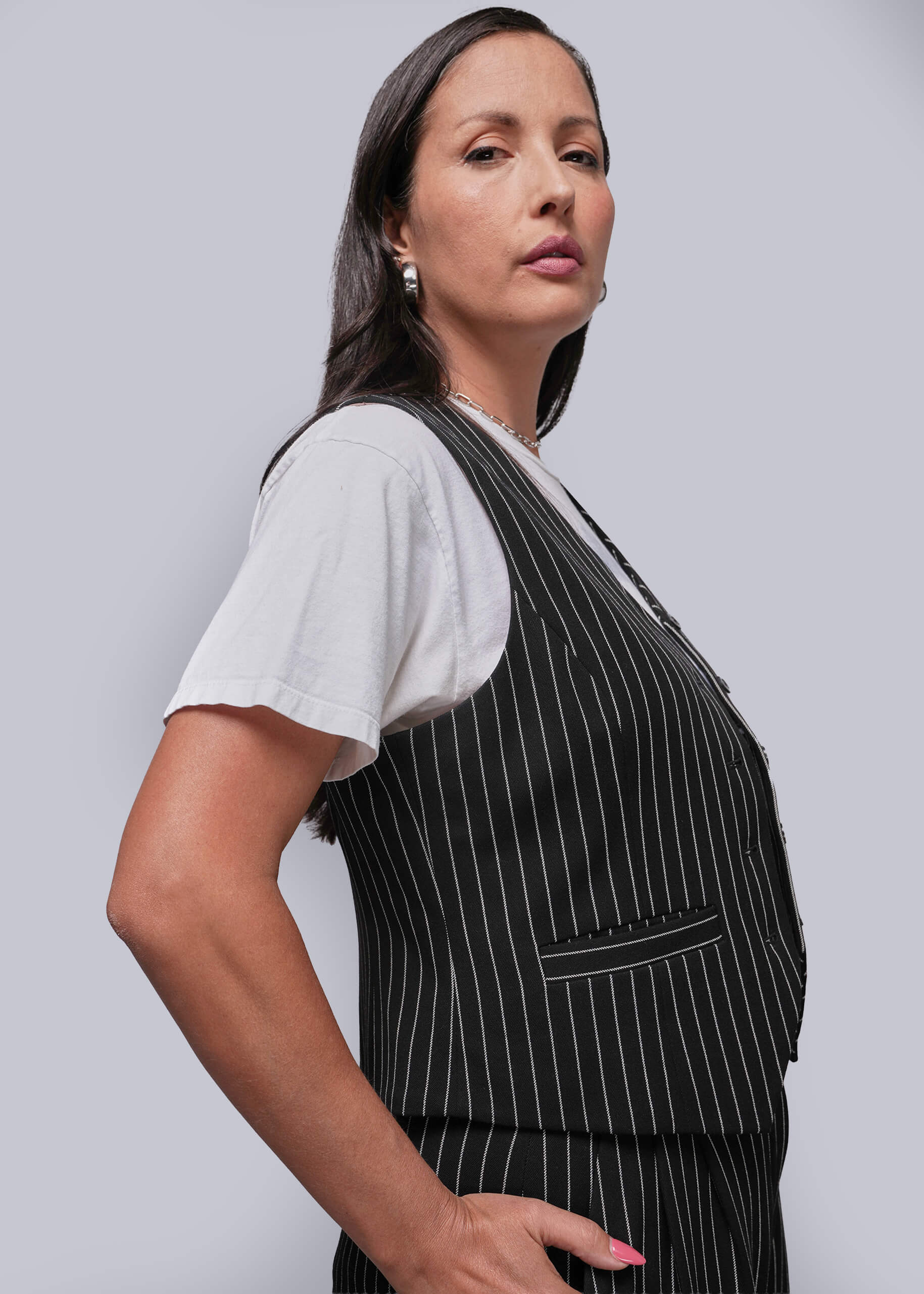 S=Woman wearing a black pinstripe apron over a white shirt on a light gray background