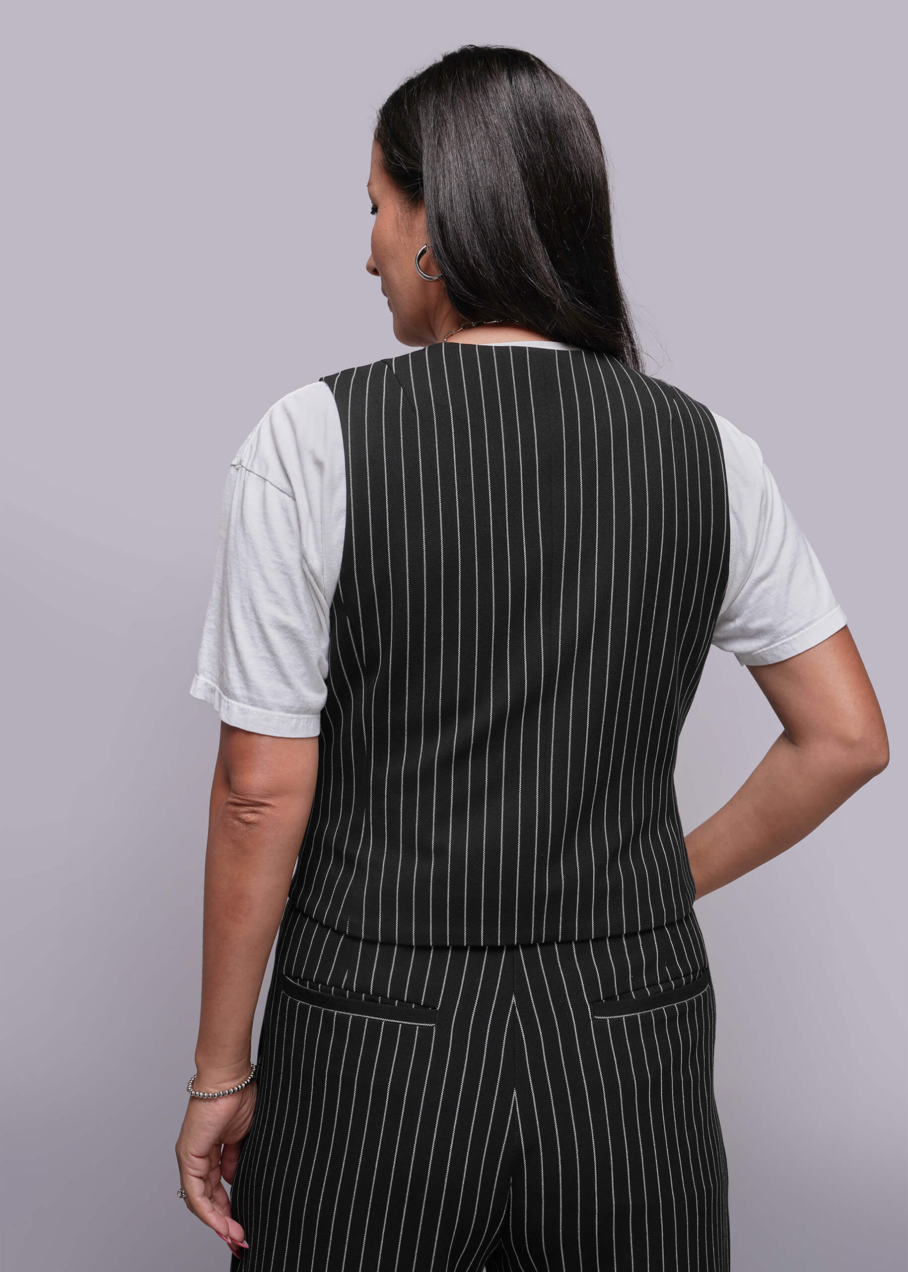 1X=Person wearing a black pinstripe vest over a white shirt on a gray background