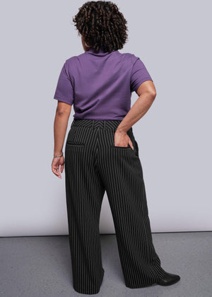 1X=Person wearing a purple shirt and black pinstripe pants against a gray background