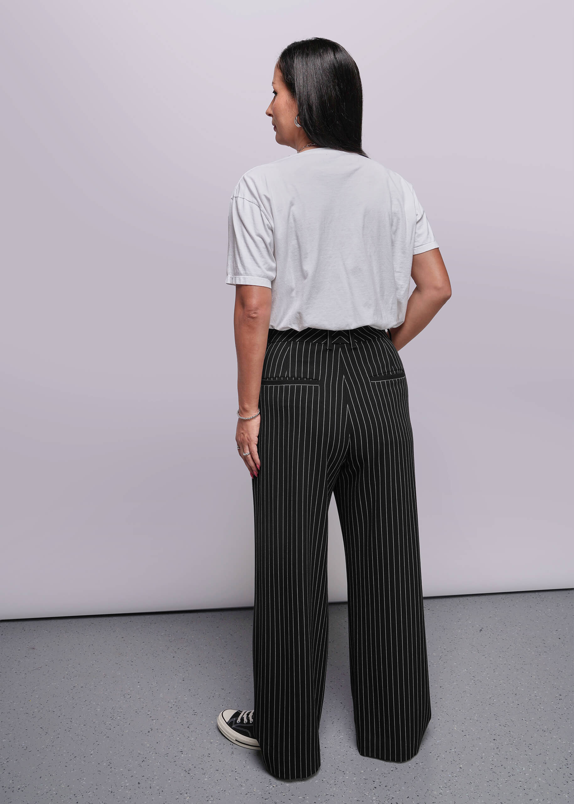 S=Person wearing a white shirt and black pinstripe pants against a plain background