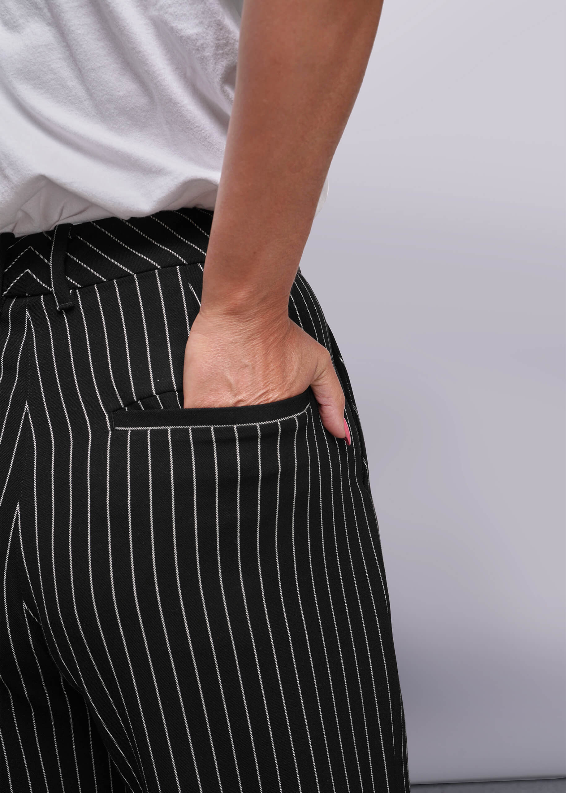S=Person wearing black pinstripe pants with a white background